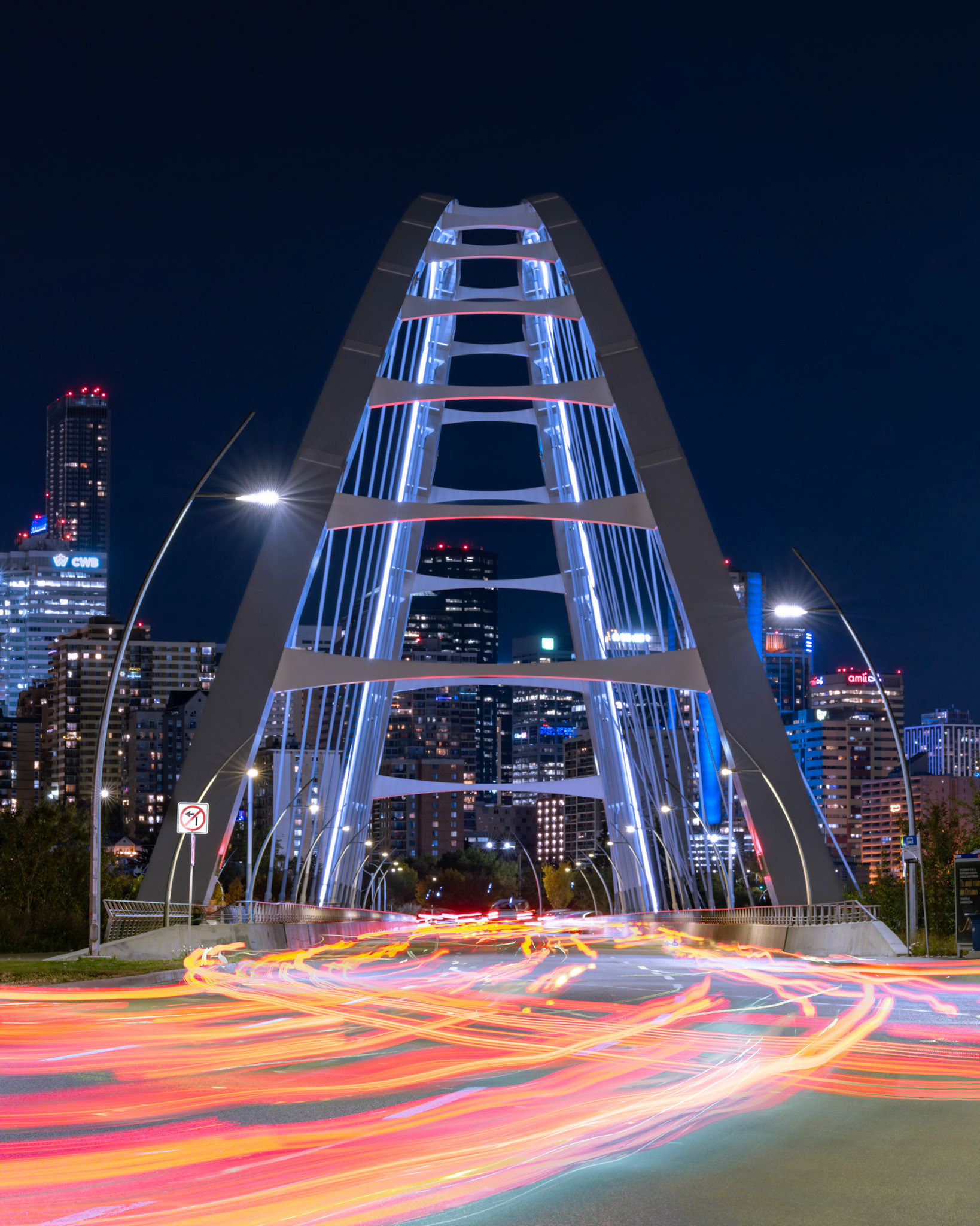 Stop-start traffic streams erratically under the Walterdale Bridge toward the heart of Edmonton as night takes hold.