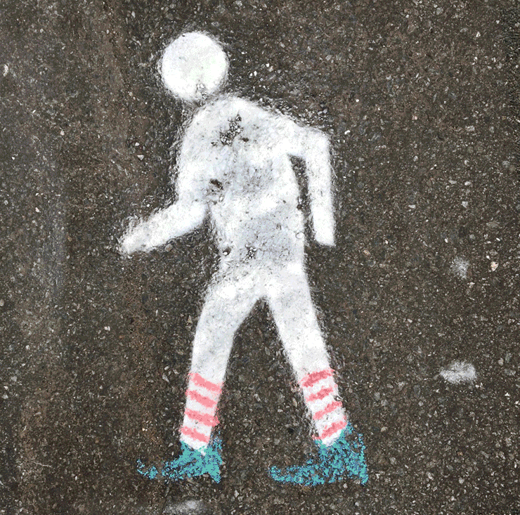 Spray chalk of a walk symbol, with a different doodles on top of the walk symbol. Some with a mermaid tail, clown nose, and broom.