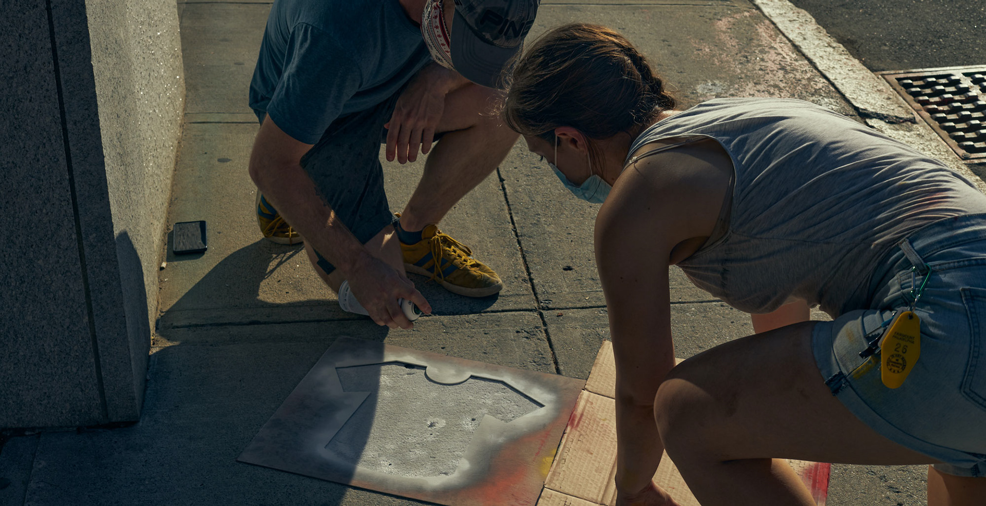 Myself and Jacob DeGeal spray painting on a sidewalk, using chalk spray paint