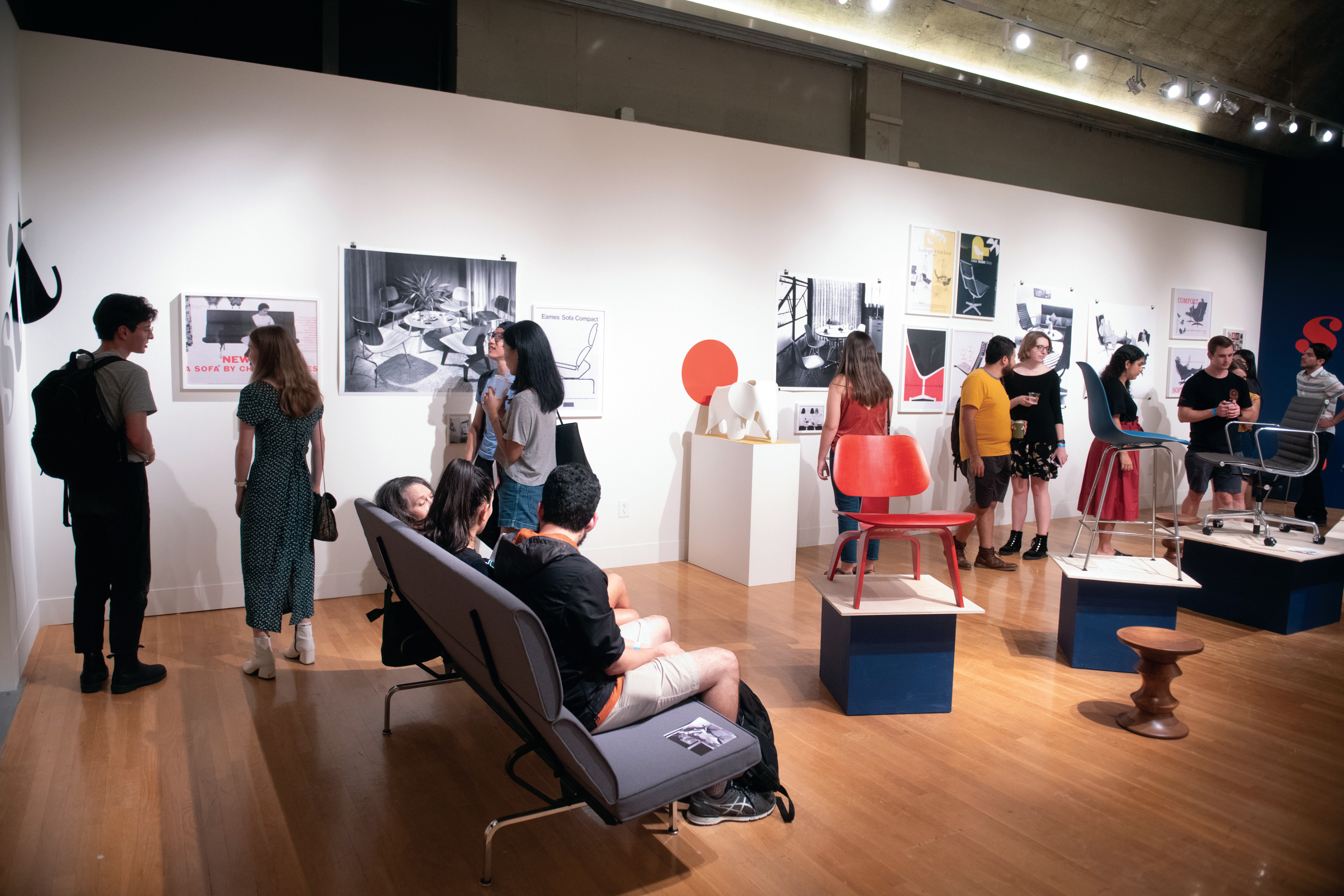 Visitors interacting in the space, looking at the all of posters, and sitting in the exhibition.