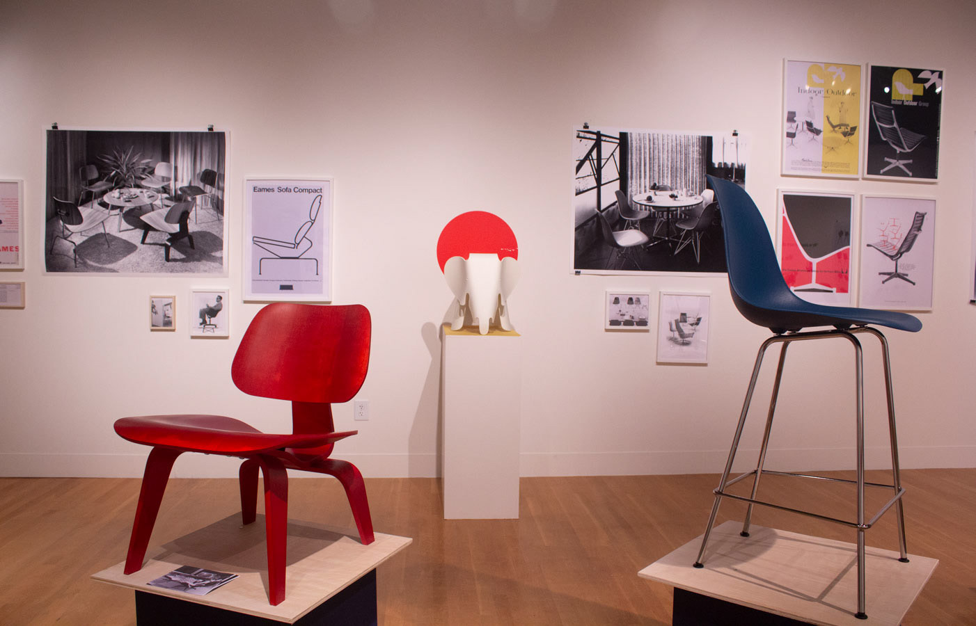 Close of up the Eames' chairs, with posters in the background.