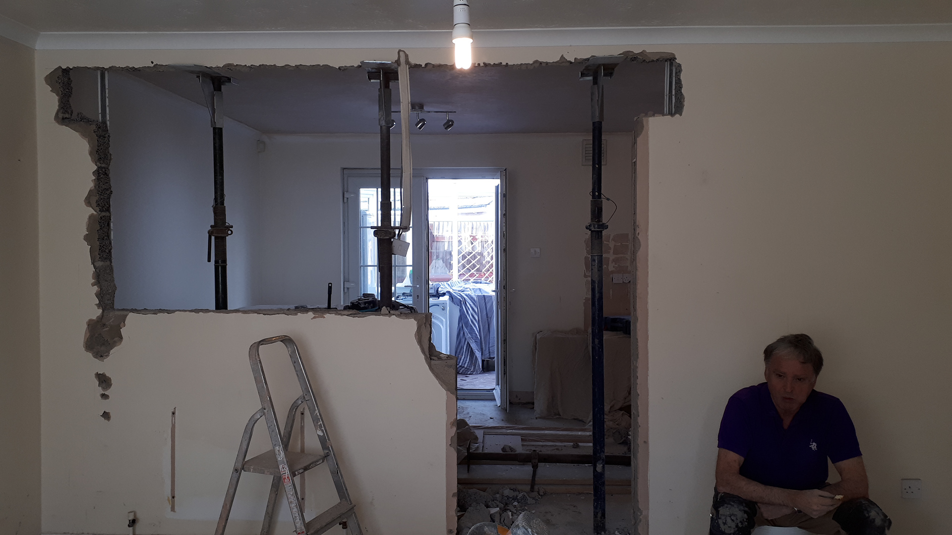 This is a picture of the ceiling being supported with Acrow props while we removed the wall. Also in the picture is Geoff, the builder who  taught me to do this, as well as to Plaster and various other building skills.