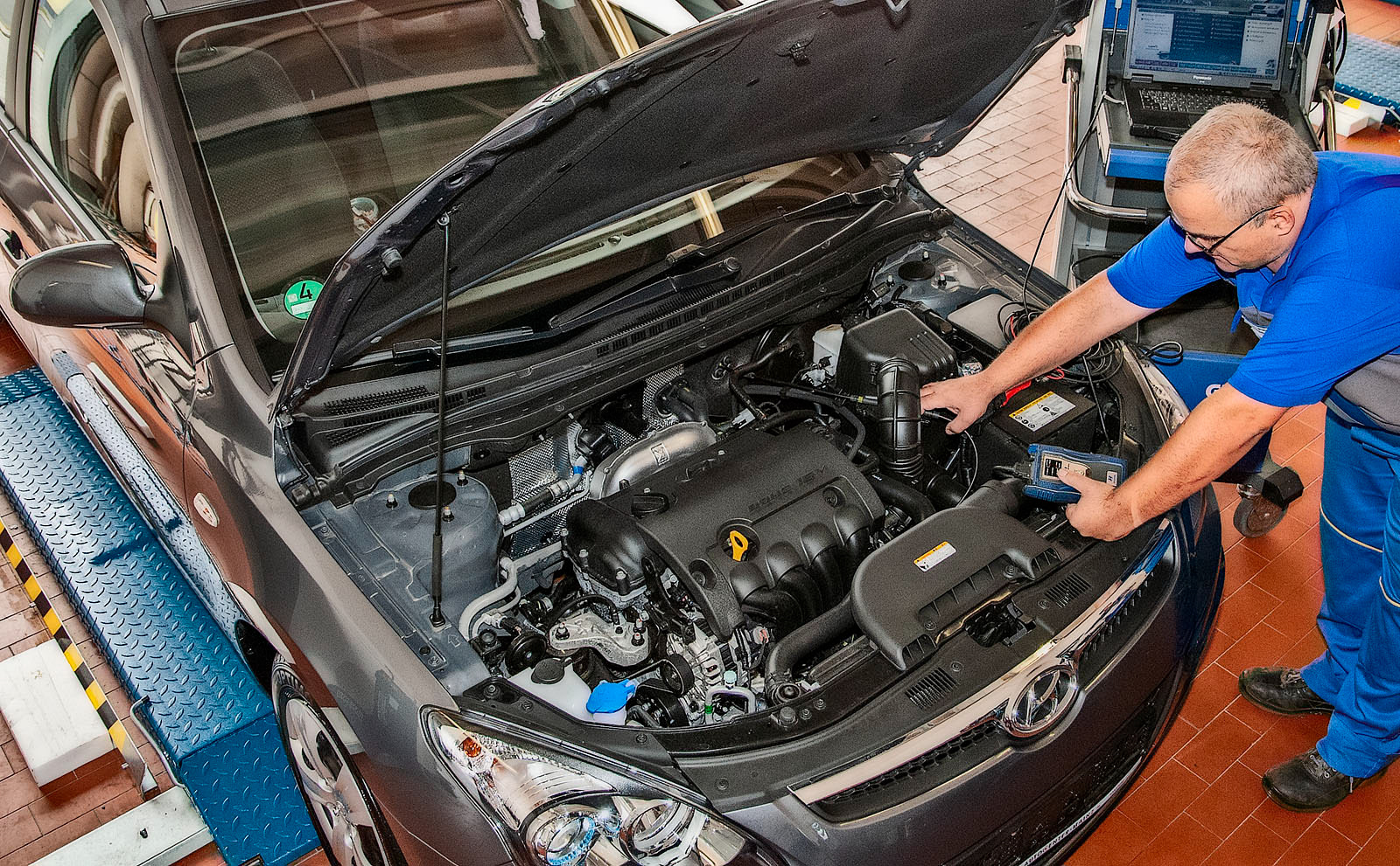Automechaniker mit Messgerät am Motor eines PKW