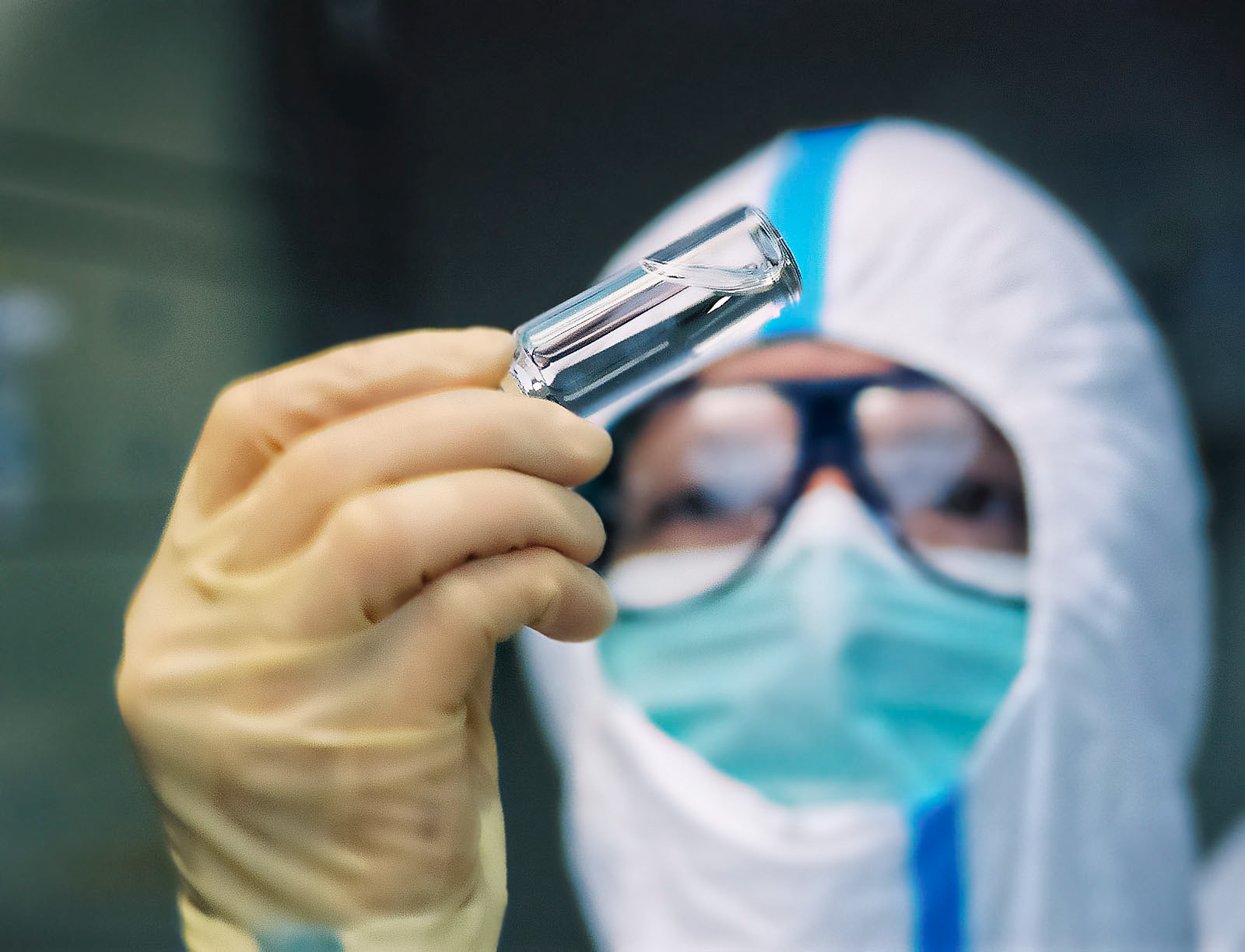 Laborant hält prüfend ein Glasfläschchen mit Wirkstoff in die Höhe