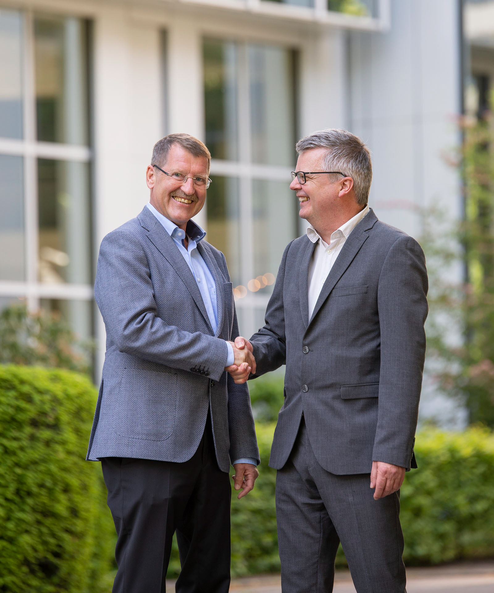 Zwei Geschäftsmänner beim Handshake vor einem Bürogebäude