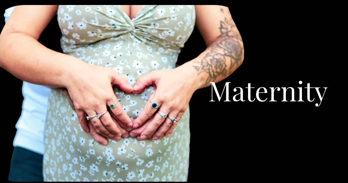 Mother shapes her hands into the shape of a heart and holds them over her pregnant belly.