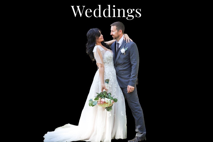 A bride hugs her grooms around the neck ith one arm and holds her bouquet down by her thigh with the other hand. The groom smiles at the bride .