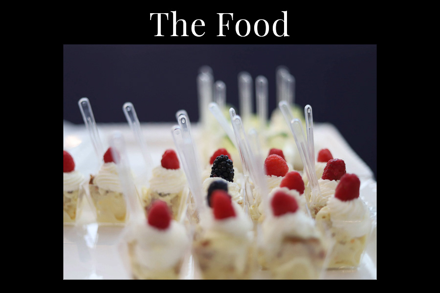 Brightly colored cake like deserrts topped with frosting and raspberries.