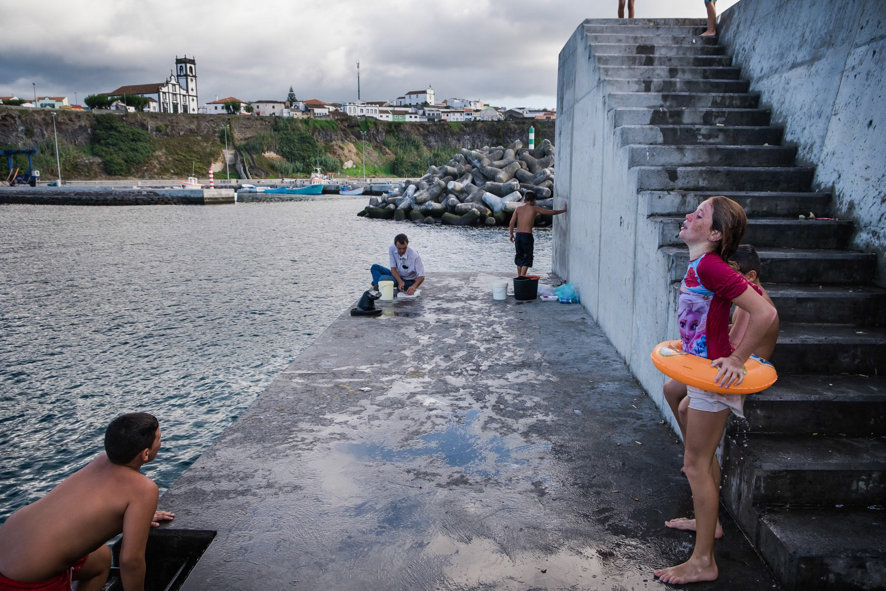 Kids playing and swimming in the port. Rabo de Peixe, Azores, September 2018
