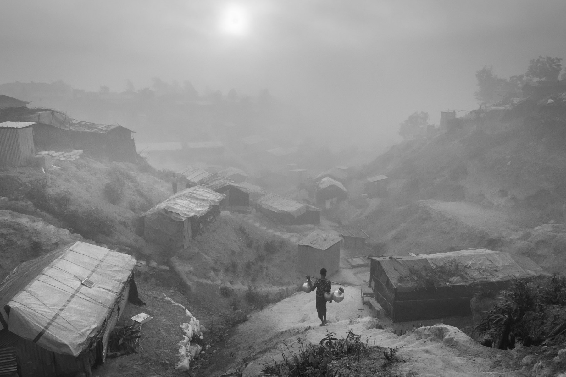 A Rohingya refugee carrying water from one of the few tube wells in the refugee camp for new arrivals. More than 650,000 Rohingya refugees have arrived in Bangladesh since August 2017. Thangkhali refugee camp, Bangladesh, March 2018