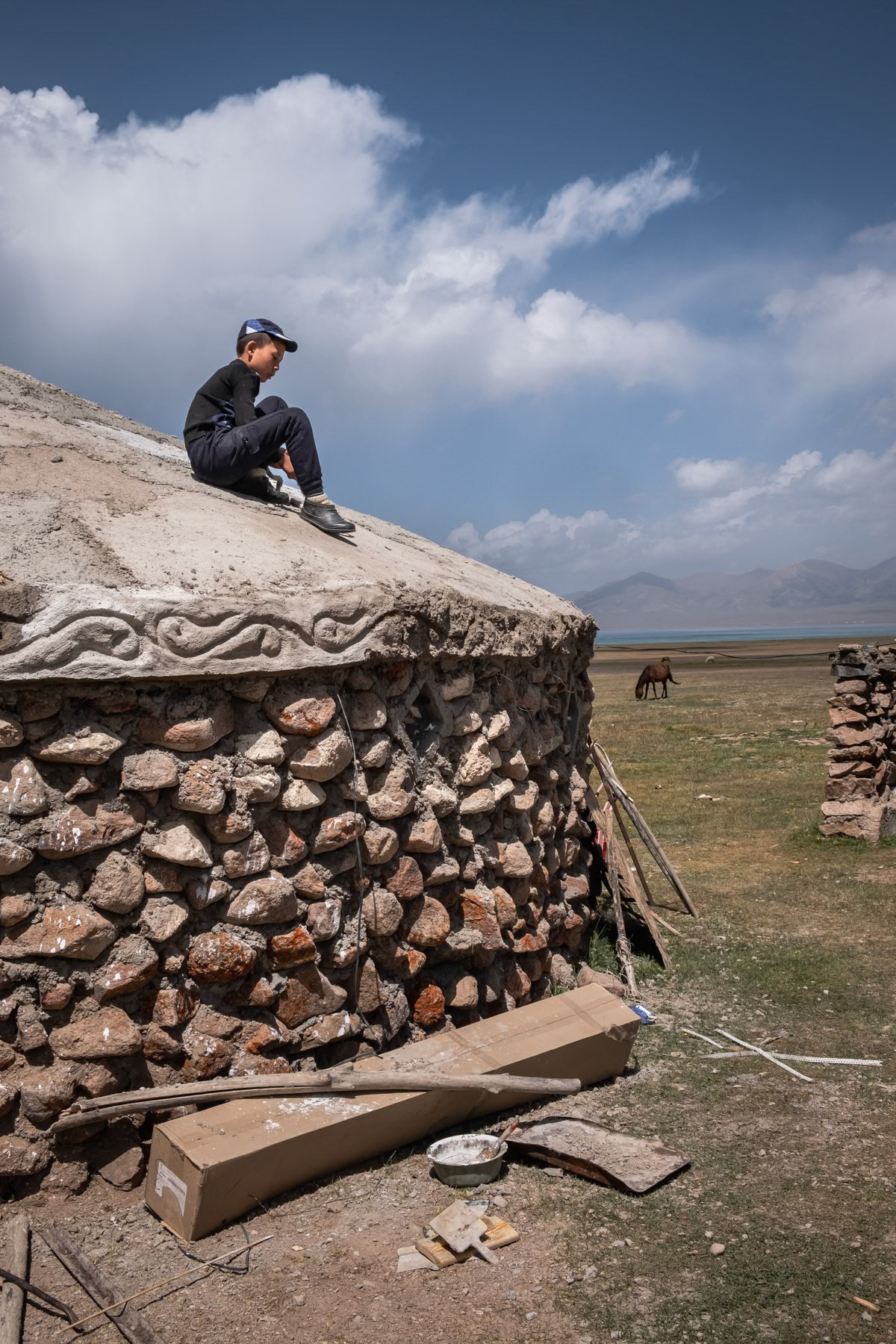 Child on top of a concrete yurt build travellers passing through Son Kul Lake 3,000 above sea level and only accessible between end of June and September. Son Kul Lake, Kyrgyzstan, August 2021