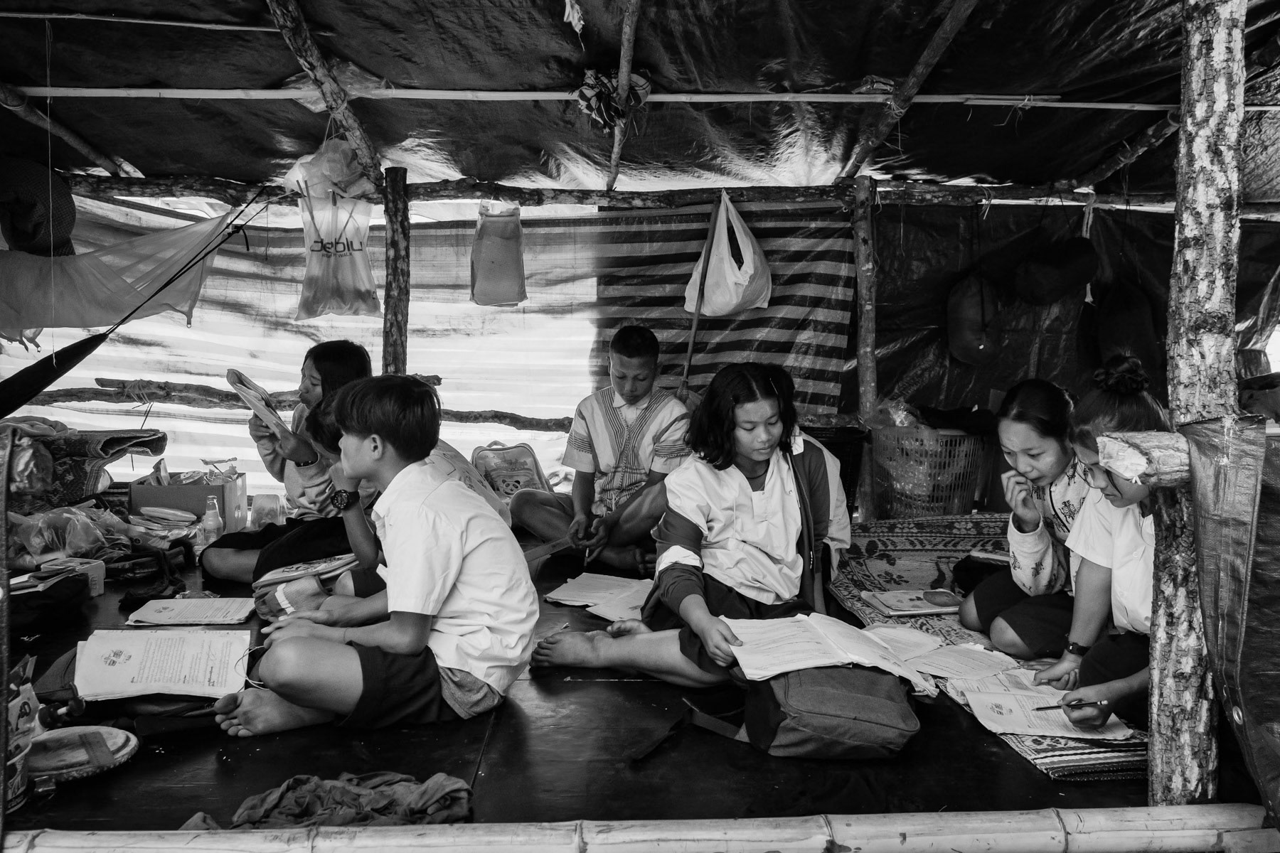 Karen children studying in improvised schools along the Thai border. The schools operate in houses or in the open under trees and not in school buildings who are frequently targetted by airstrikes by the military regime. Htee Baw Kaw IDP camp, Kayin State, Myanmar, January 2024