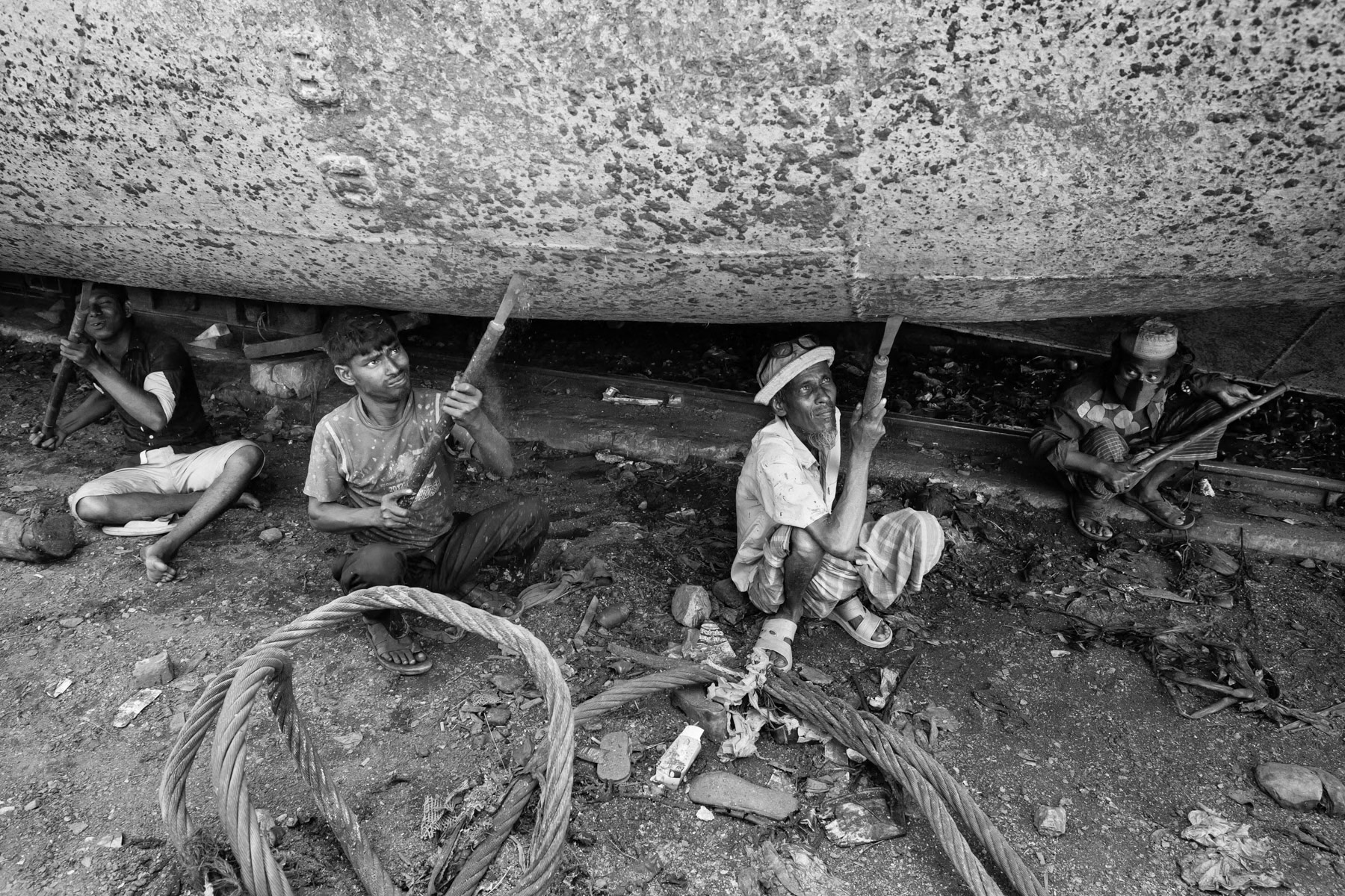 Scrubbing old paint from the hull, Dhaka shipyards, Bangladesh, May 2015