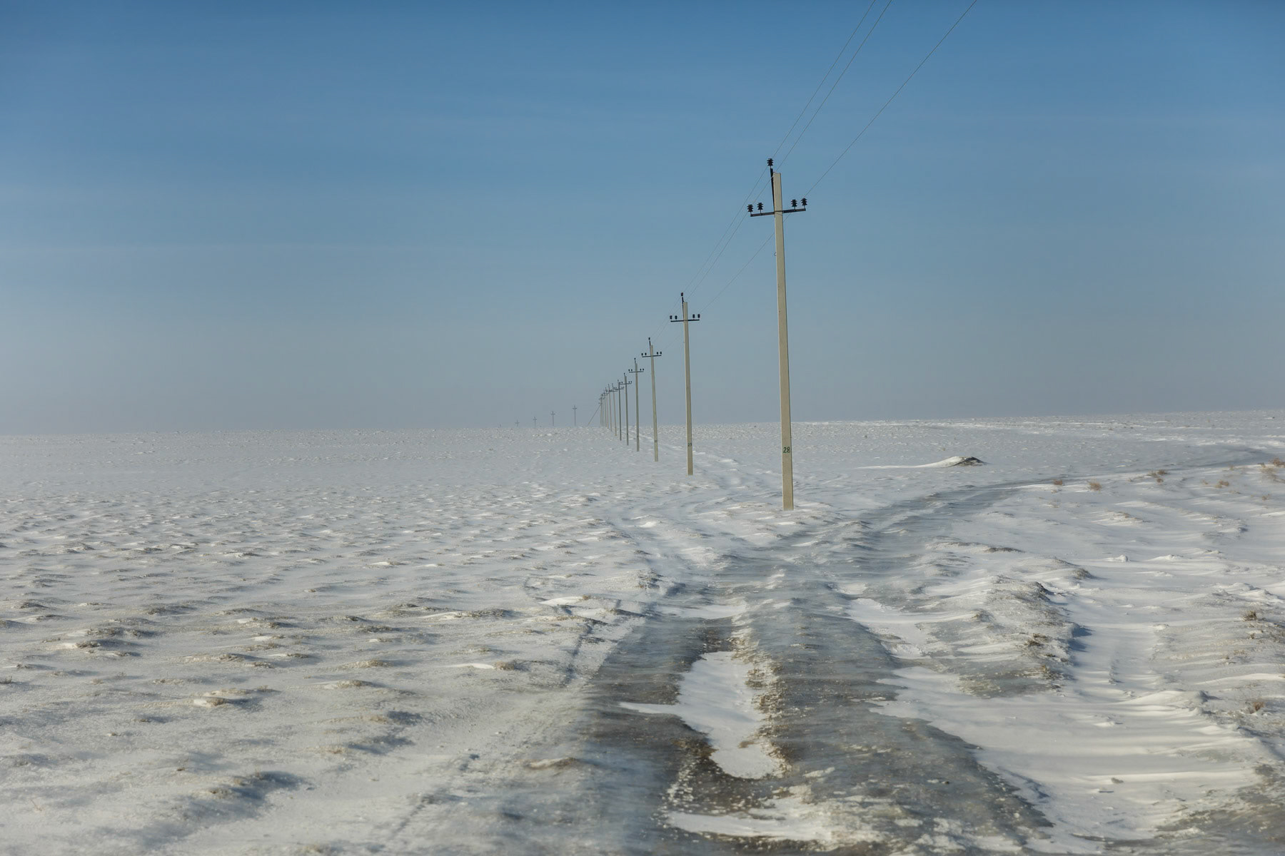 The Aral Sea is a lake that was once the fourth largest in the world. It is a lake with no outflow. The Aral Sea is located between Kazakhstan and Uzbekistan in the former Soviet Union. The Aral has been shrinking since the sixties after the rivers that supply it were diverted for Soviet irrigation projects for Uzbek farmlands and cotton plantations. By the end of the 20th century the Aral Sea had declined to 10% of its original size dividing it in small patches of water and ever increasing dried up desert stretches. In an effort to replenish the North Aral Sea and revive a deciminated fishing industry, Kazakhstan has completed a dam project in 2005. Water levels have started to rise and salinity decreased, making fishing viable again and attracting more and more people from surrounding areas again. During the harsh winter fishermen stay for periods of 3 months on the frozen lake and come fishing from places well beyond the Aral Sea villages. In summertime fishing is done with small boats. What has often been called as one of the worst environmental disasters is slowly experiencing a modest revival for the population of the remote North Aral Sea villages in Kazakhstan. Fozen tracks in the Aral steppe. Aral Sea, Kazakhstan, January 2019