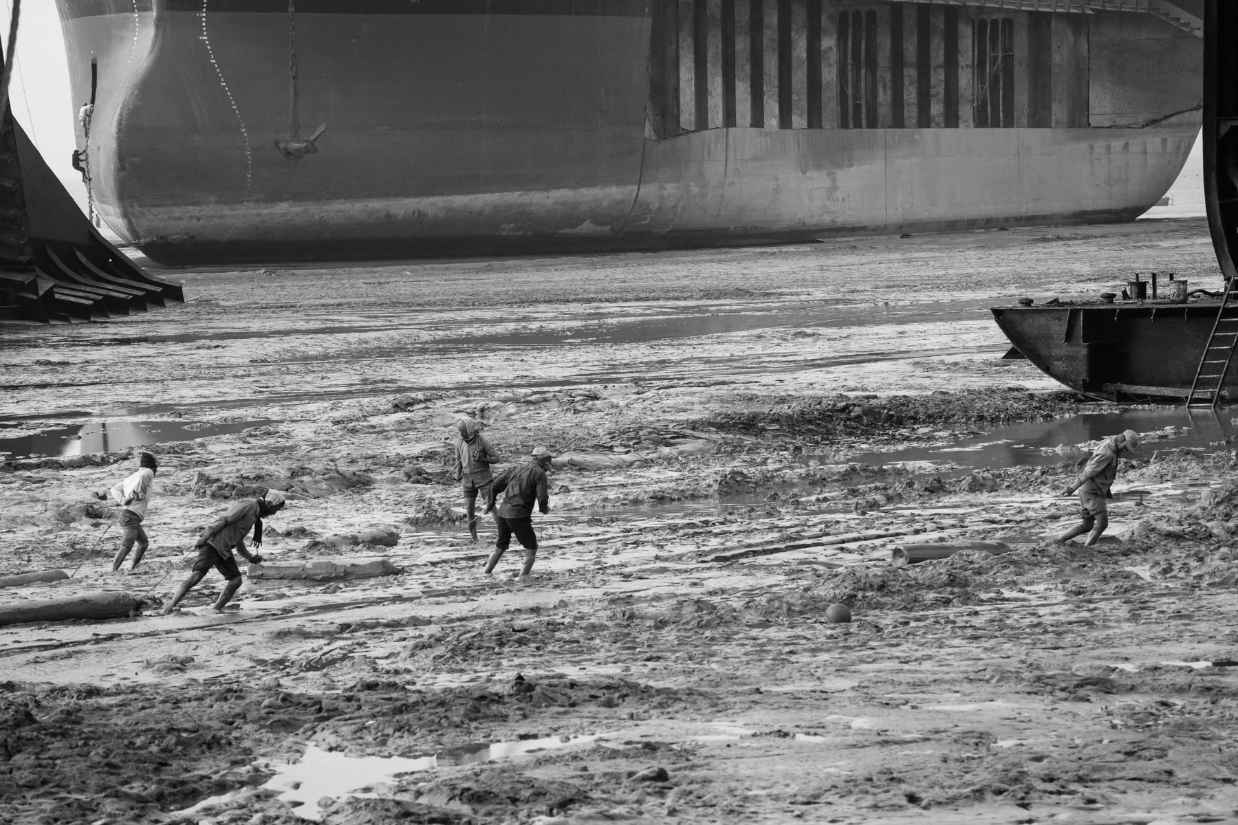 Workers moving gaz tanks through the mud, ship breaking yards, Bangladesh, December 2015