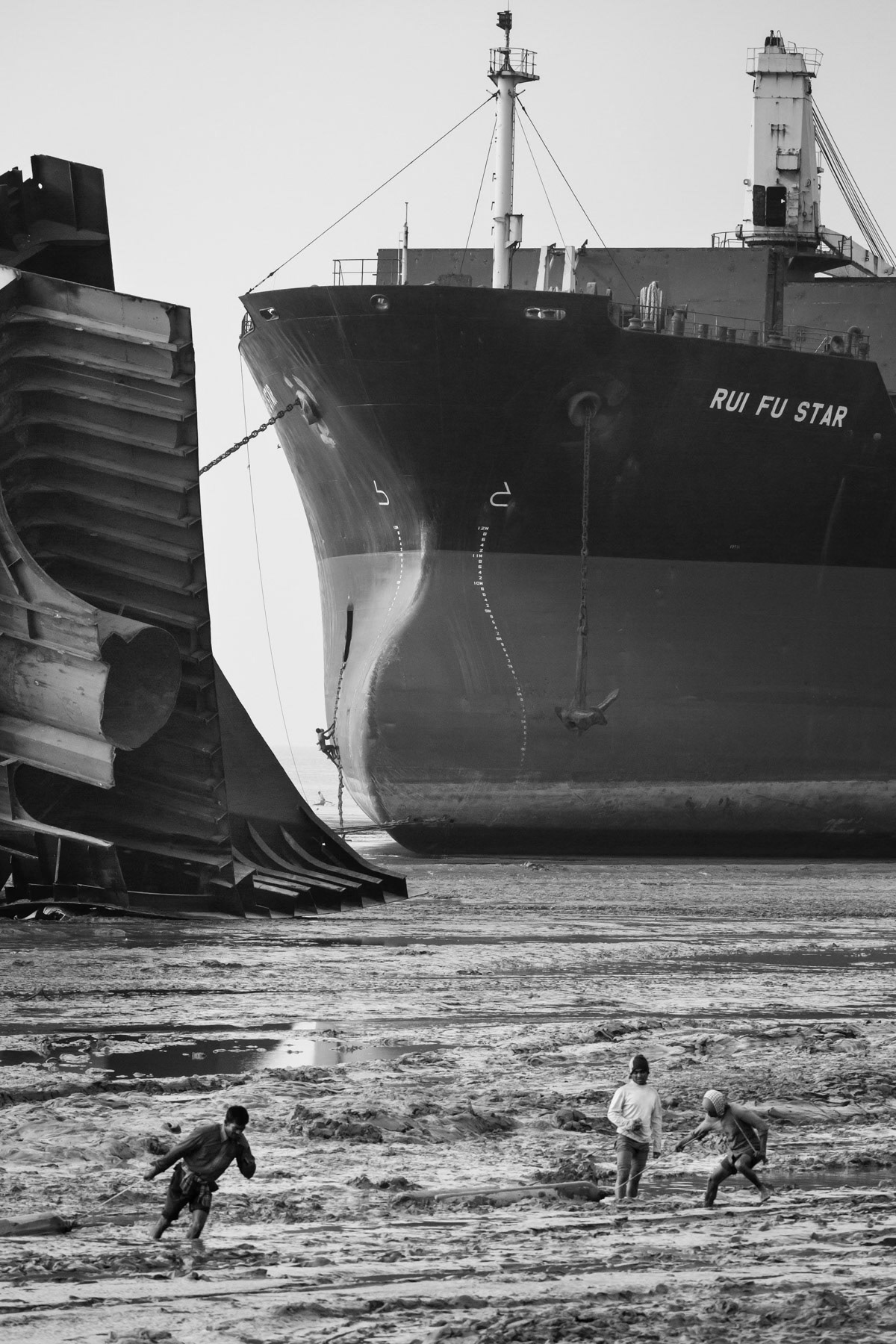 Workers moving gaz tanks through the mud,. The ships will be entirely dismanteled manually and cut up in pieces on the beach, Bhatiary ship breaking yards, Bangladesh, December 2015