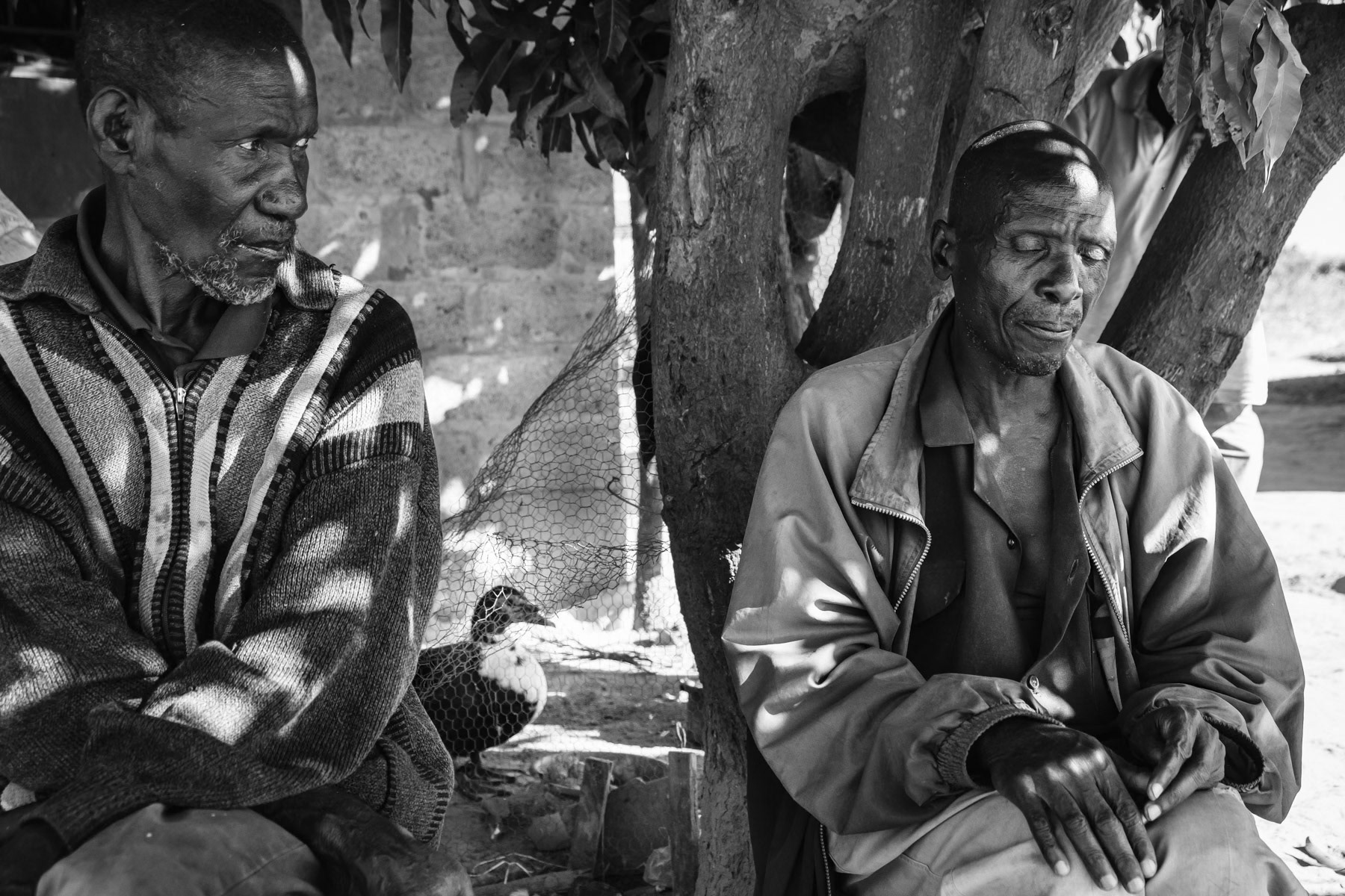 Senior miners in front of a small house that was built by UN Habitat for vulnerable communities. Retired miners do not have pensions and depend on family members or social services to survive. Makululu Township, Kabwe, Zambia, May 2021