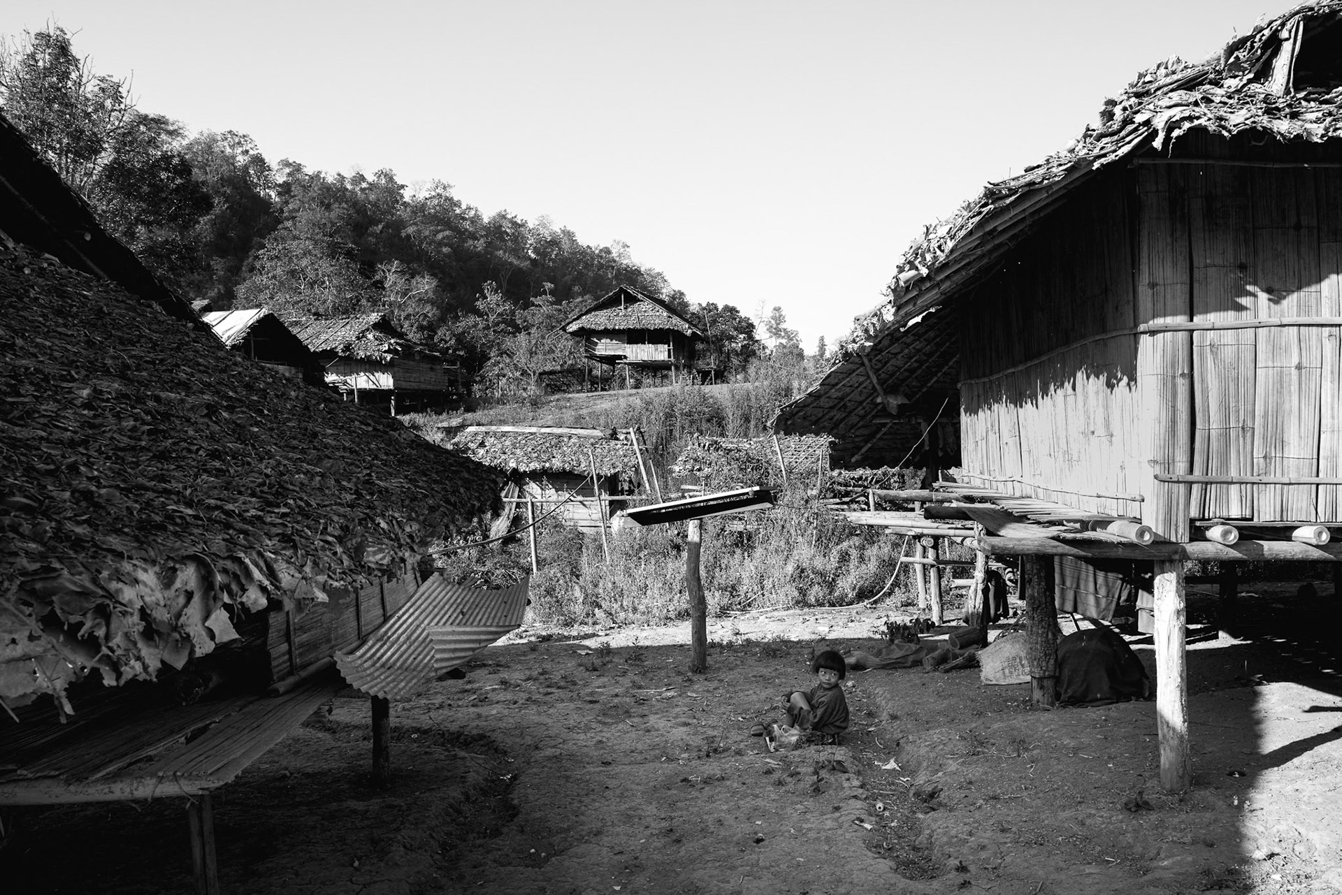 A view of the camp’s perimeter shows the proximity of the dense Karen State hills. This terrain provides cover, but the open spaces between huts remain vulnerable to the "silent" threat of loitering munitions and drones. Kayin State, Myanmar, January 2026