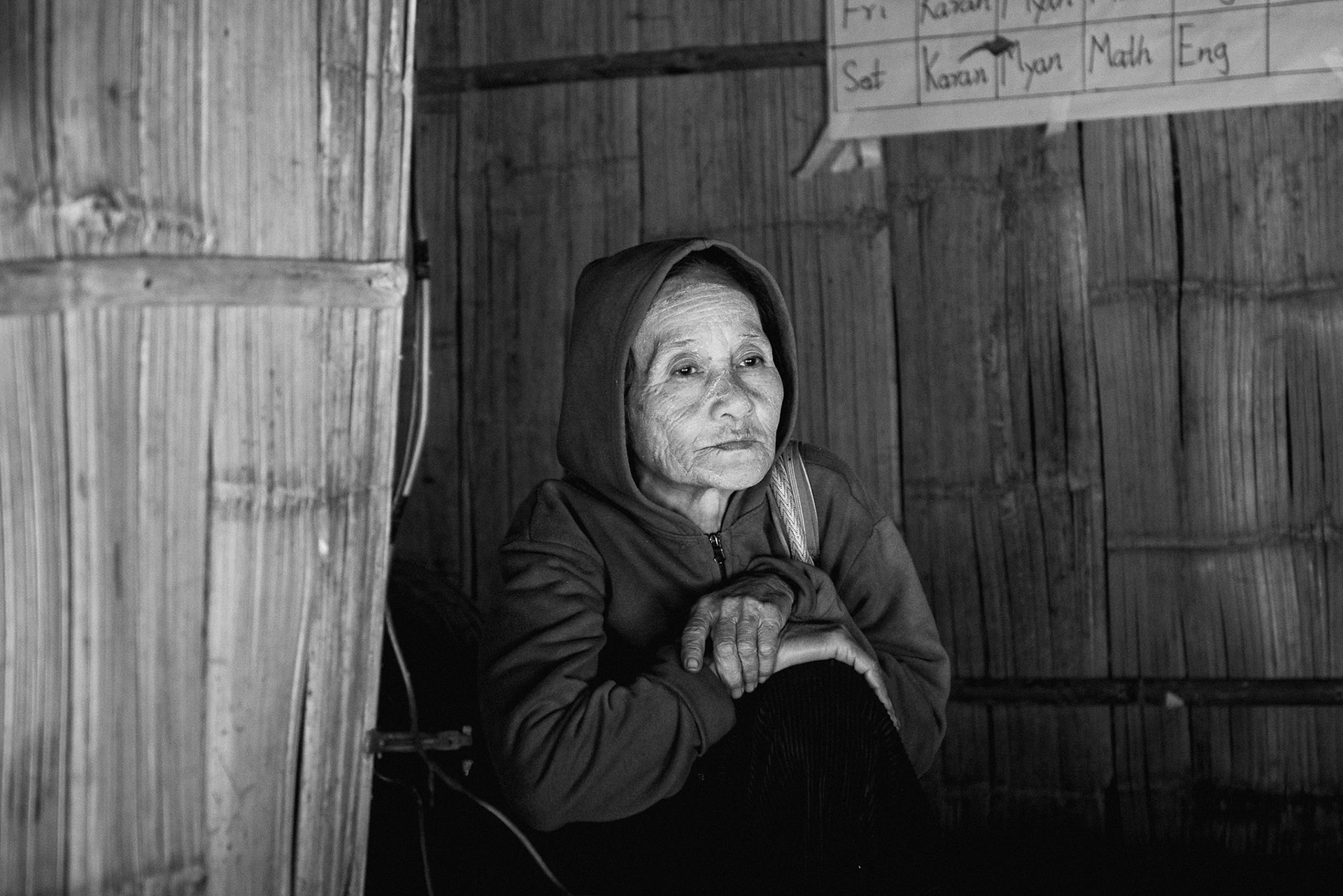 An elderly woman sits inside the temporary health post at Kanele Htaw. In a conflict zone where drone strikes are a daily reality, medical facilities are both a lifeline and a high-risk location. Kayin State, Myanmar, January 2026