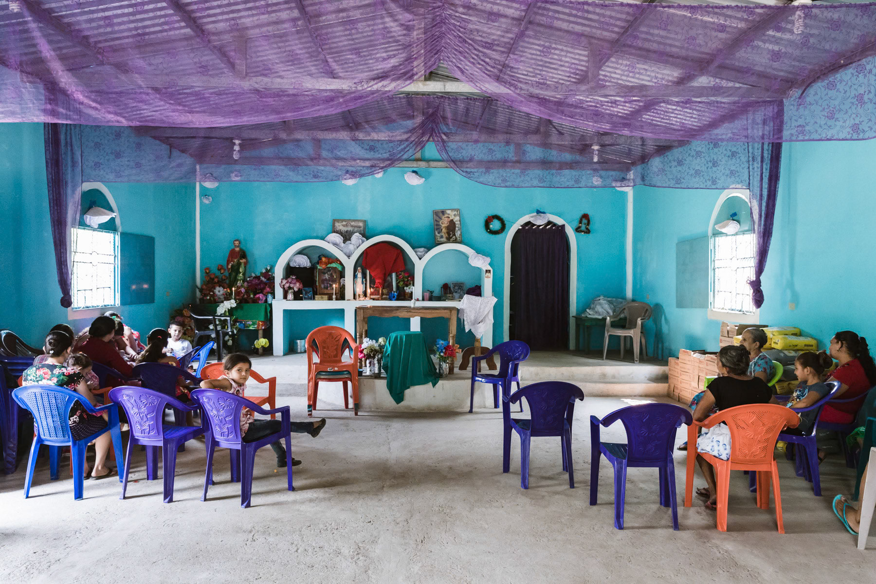 Villagers waiting for the priest to start the Sunday mass. The polulation of Corazor are Salvadorian but the village is now part of Honduras. The El Salvadorian President gave by decree in 1979 several villages in Chalatenango to Honduras that were used as guerilla bases to fight the right-wing government. This move also isolated the guerilla of the hinterland. The territory was never returned and remains a part of Honduras as confirmed by the International Court in The Hague. Corazor village in Honduras, April 2019.