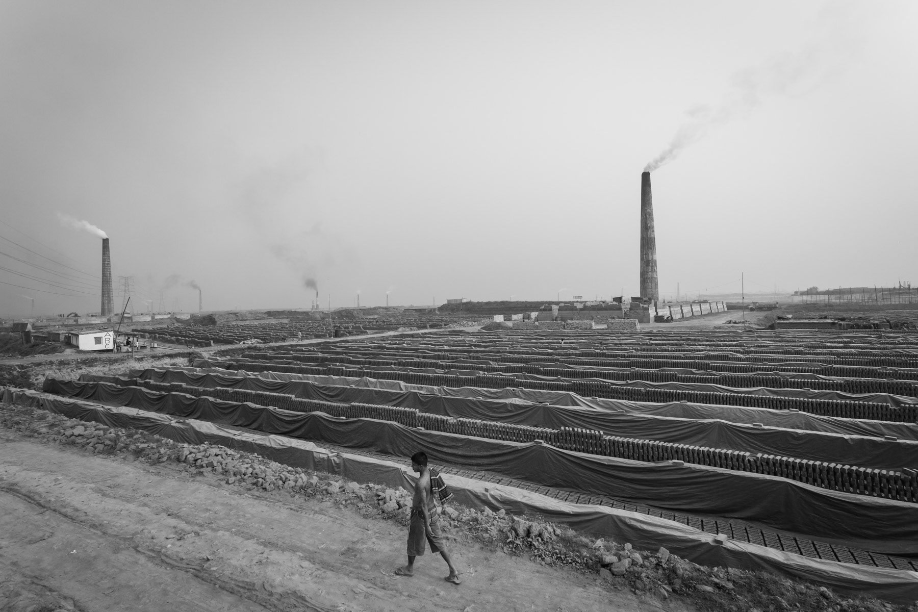 Heavy labour in the numerous brick kilns are mainly done by women. In particular before the production season starts and the brick kilns and storage places need to be sorted. Entire families migrate to work and live during the seanon at the brick kilns. The brick production season runs during the dry months from December to May. All labour is done manually. Amin Bazar brick kilns are the main supplier site for the booming contractuction sector in Dhaka, and also the cause of extreme air pollution in the capital, Bangladesh, December 2015