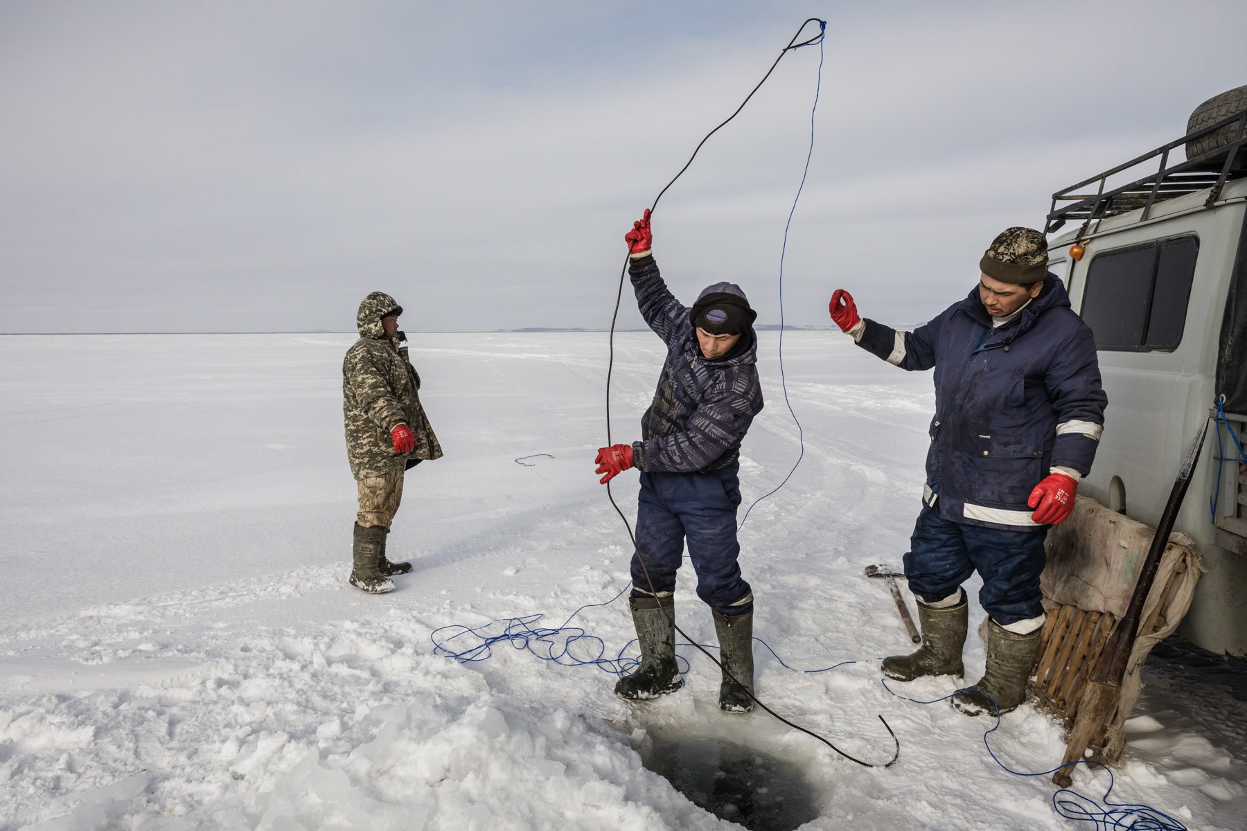 Fishermen retrieving the net through the hole in the ice. Kazakhstan, January 2019
