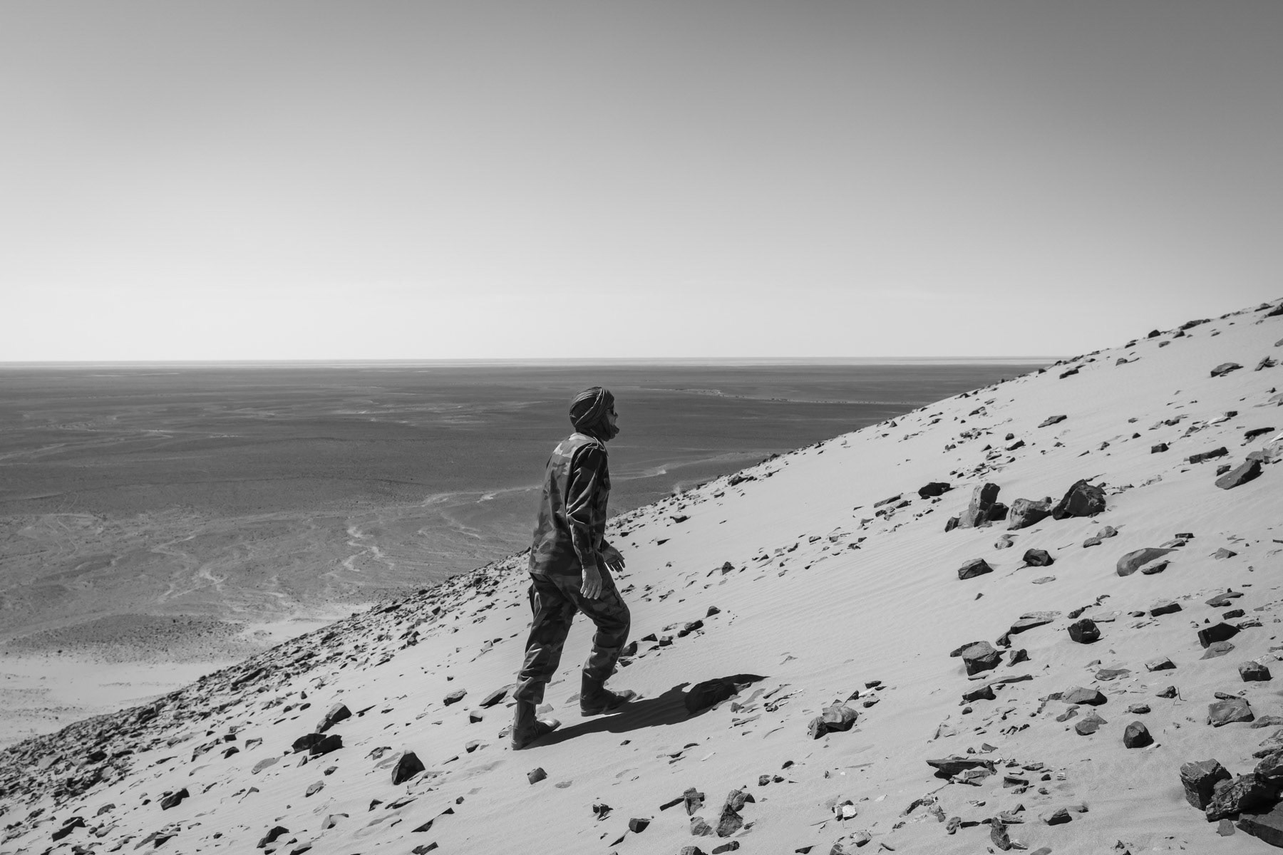 Sahrawi soldier taking position on a high point to overlook artilley strikes towards Maroccan positions 5 km away engraved behind a 2,700 km long sand berm, de facto dividing the Western Sahara from North to South and forming probably one of the longest active frontline in the world. Frontline, Western Sahara, October 2021