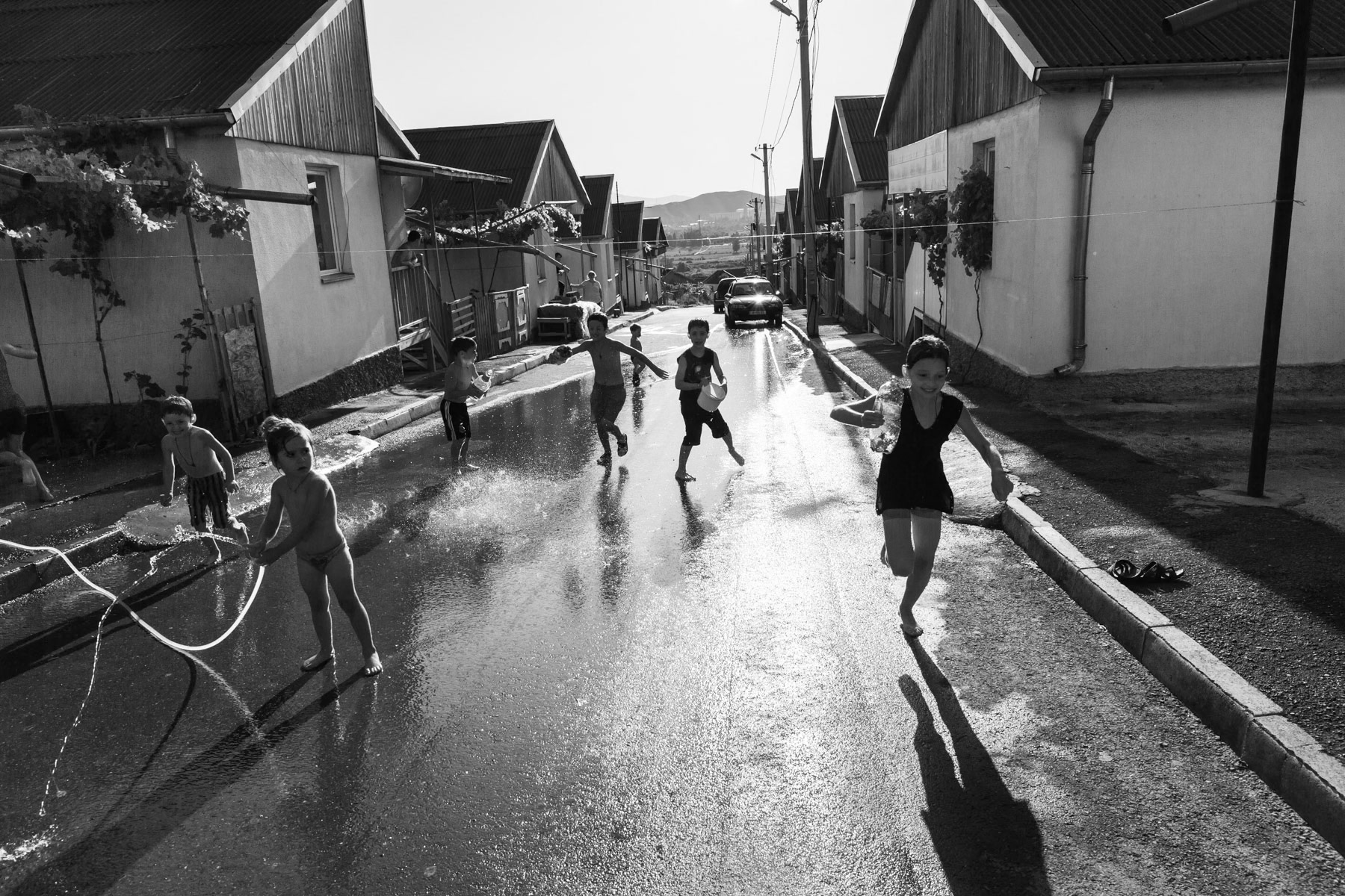 Displaced children enjoying playing with water during the summer heat. Settlement for IDPs from nearby South Ossetia, Gori, Georgia. August 2016