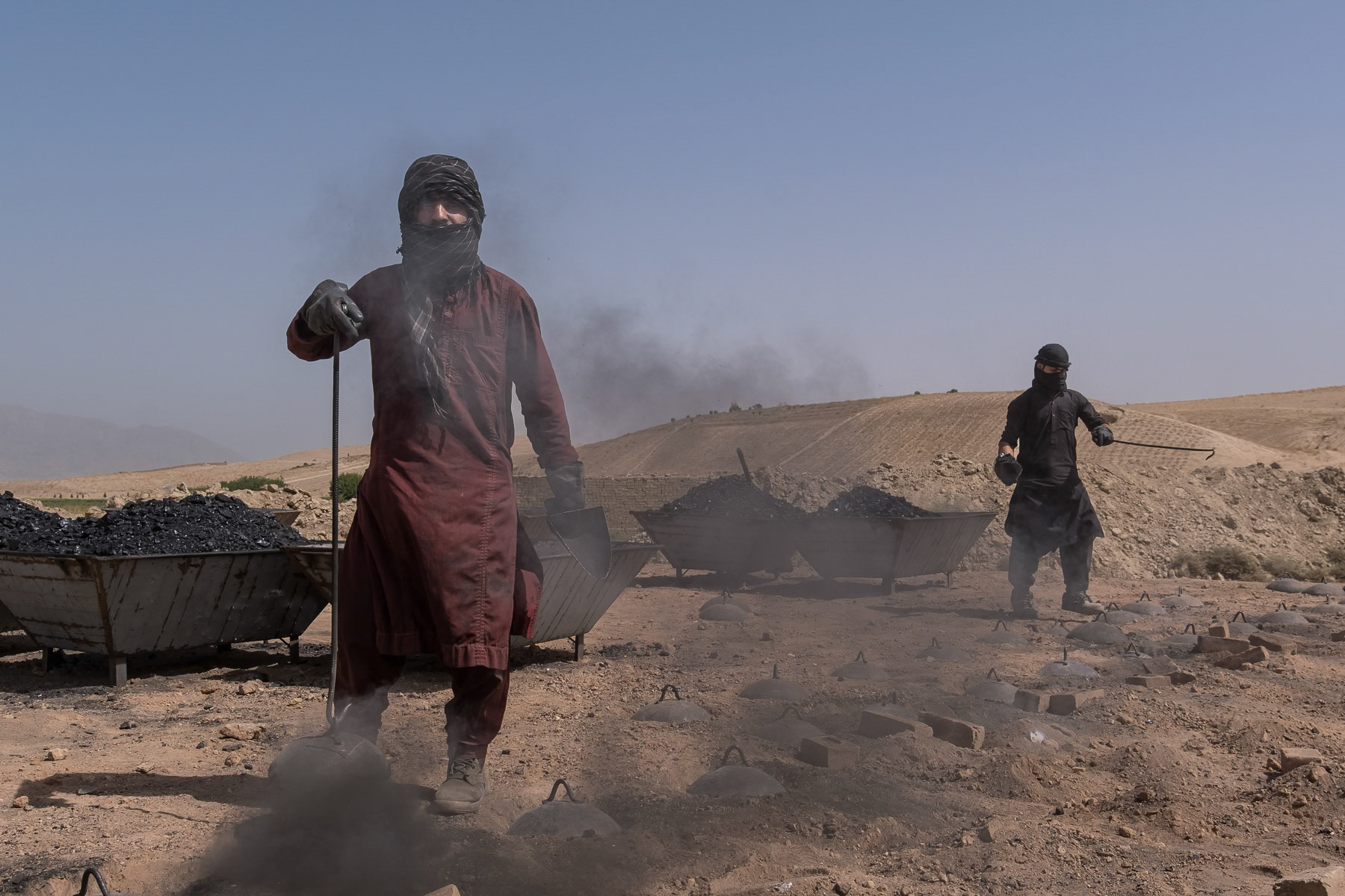 Brick kiln workers in charge of keeping the brick oven burning. The outside air temperature around the kiln is well beyond 50 degrees celcius. Balkh, Afghanistan, September 2024