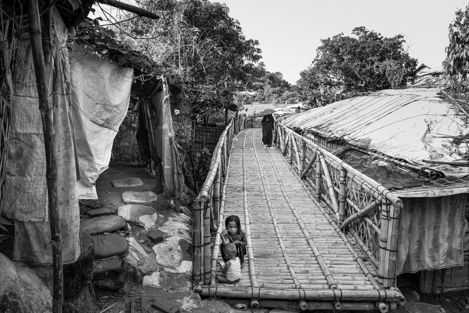 A bamboo bridge spans between two sectors of Camp 7 in Kutupalong, connecting densely packed shelters across the hilly terrain. Kutupalong refugee camp, Ukhiya, Bangladesh, September 2025