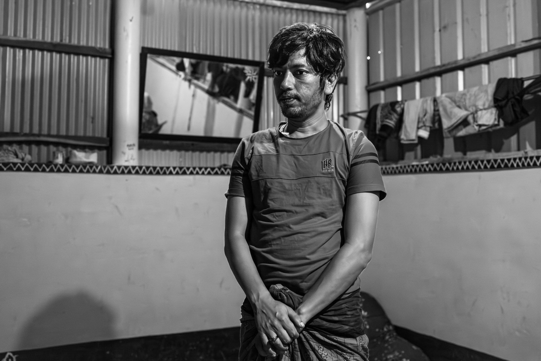 Shomsul, from Laway Daung in Buthidaung Township, stands for a portrait in Bangladesh, where he has lived since fleeing the mass expulsion and widespread violence against Rohingya communities in 2017. He recounts ongoing fears for relatives who remained in Myanmar, including recent attacks on his home village and the disappearance of community members at the hands of the Arakan Army. Kutupalong refugee camp, Ukhiya, Bangladesh, September 2025