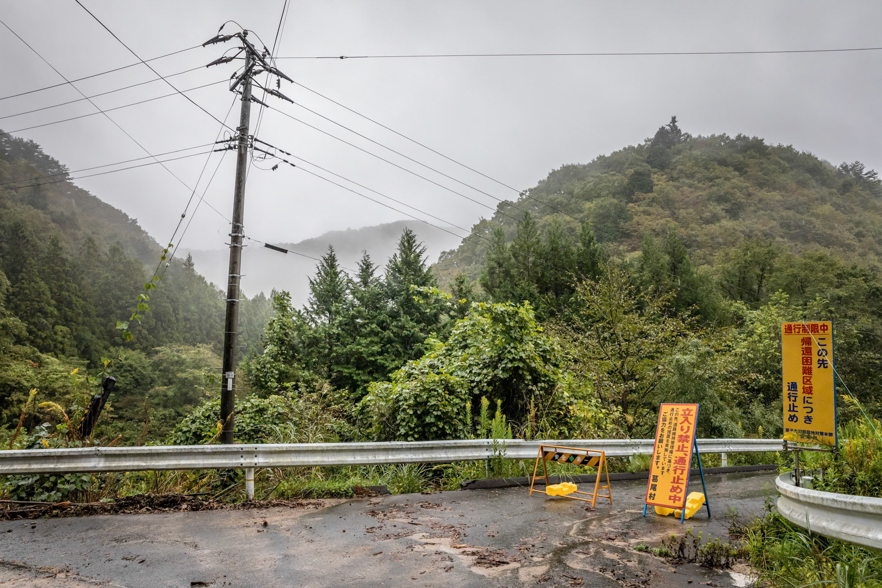 Sealed off area along route 50 crossing the mountains. The entire area in the woods and mountains are no go zones as radiation levels are still to high. Those areas in the hinterland will most likely remain off limit forever. Route 50 between Namie and Katsurao. Fukushima Prefecture, Japan, October 2019