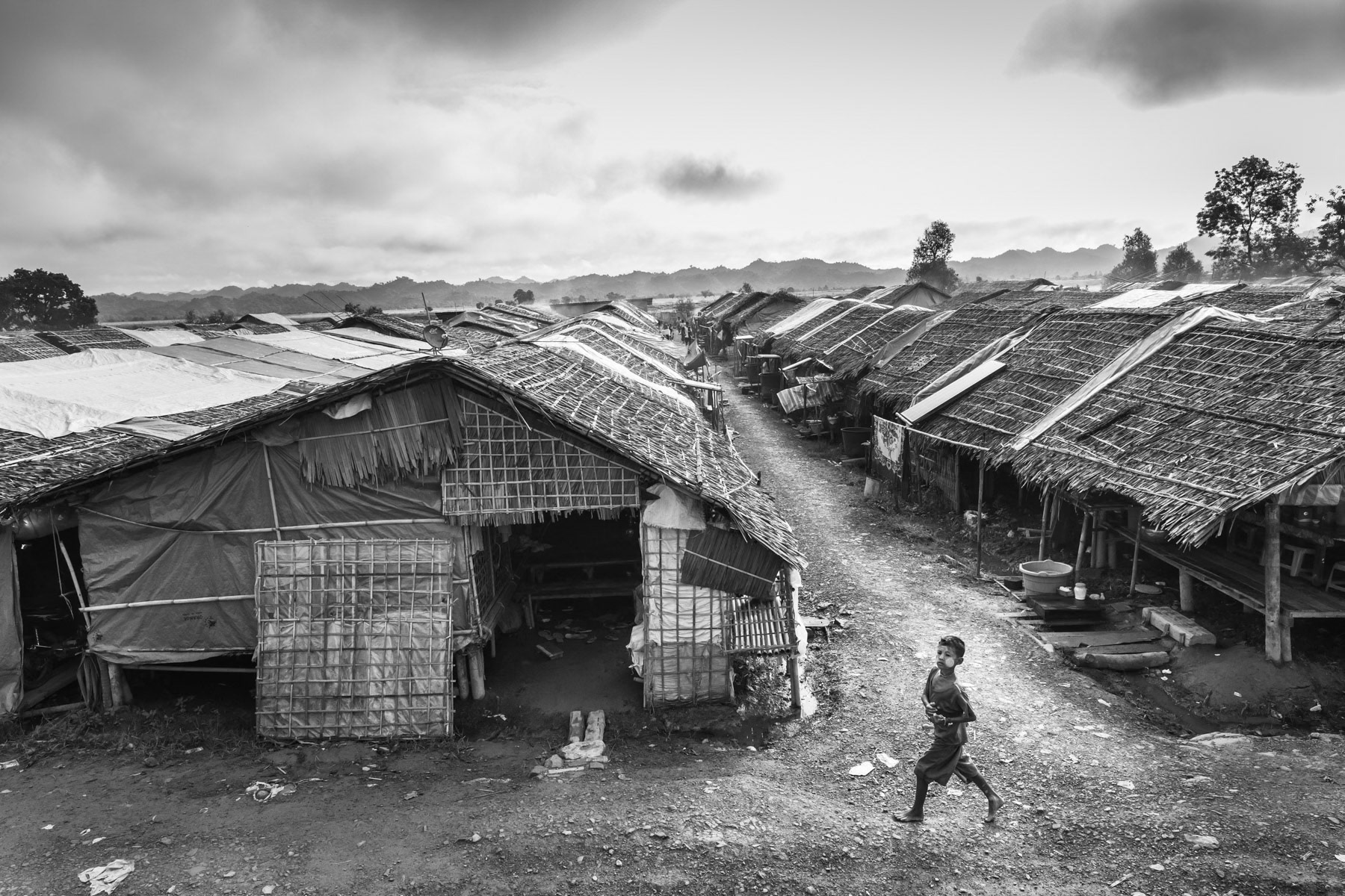 Rakhine State, also called Arakan, is again the theatre of armed conflict less than two years after the military's brutal campaign against the Rohingya, which led to the exodus of more than 750,000 people and accusations of genocide. More than 250,000 Rohingya are presently still in Rakhine State scattered in villages and are frequently caught and victim of the armed conflict between Arakanese rebel fighters and the Myanmar military. This time the renewed violence started when in January 2019, police stations were attacked by the Arakan Army (AA) and marked a new chapter in Myanmar's never-ending armed conflicts between ethnic rebel groups and Tatmadaw, the Myanmar military forces. The Arakan Army (AA), established in 2009, is an ethnic Rakhine, religiously Buddhist armed group. AA is part of the Northern Alliance together with Shan ethnic armed groups and the Kachin Independence Army (KIA) and was till 2019 based in Laiza, the headquarters of KIA, in Kachin along the Chinese border where it was training and fighting against government troops alongside KIA. When attacks started in Chin and Rakhine State in 2019, the gravity point of AA swifted from Kachin to Rakhine where they benefit of widespread popular support. With more than 20,000 soldiers, AA, is one of the largest ethnic armed group actively fighting the Myanmar military forces. The ongoing conflict in Rakhine has so far been tightly quarantined from the international community and journalists. An unprecedented government-imposed internet blackout since June 2019 has rendered available information rare and hampered humanitarian assistance due to access and communication restrictions. Amid escalating clashes between AA and the armed forces, and the alleged military abuses against the population, the number of civilian internally displaced persons (IDP) is more than 100,000 all over the region with concentrations in Mrauk-U, Kyauktaw, Rathedaung, Buthidaung, Minbya and Ponnagyun townships. With very limited humanitarian access, squalid camp conditions and the proximity of combat activities, often only few kilometres from the camps, the IDPs but also the general population gets more and more entangled in a very precarious situation with no solution in sight. During the first months of 2020 the conflict has substantially intensified with daily clashes, shelling, civilian casualties, and a more than doubling numbers of displaced persons. Largest IDP camp in Mrauk-Oo township. Nearly 3,000 Arakanese have sought refuge from 12 nearby vilages that are now on the frontline. Over 40,000 people have fled their villages in Rakhine since the armed conflict between the Arakan Army (AA) and government troops started in January 2019. Thein Nyo IDP camp was set up in April 2019, water is only available from a pond. Thein Nyo, Mrauk-Oo township, Rakhine State, Myanmar, October 2019