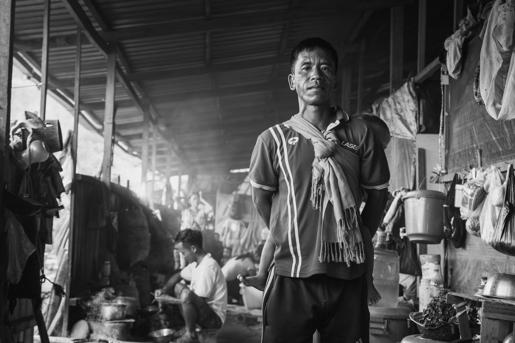 Chin Refugee and his child in a refugee shelter along the Indian Burmese border. With ever increasing airstrikes against villages, more and more people cross into India seeking safety and refuge. Hill camp for Chin refugees mainly from Falam and Kalay. Zokhawthar in Mizoram, India. May 2023