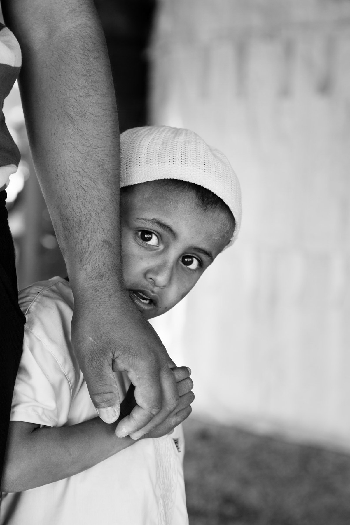 Boy holding his father's hand, Khan Al Ahmar Bedouin encampment in the West Bank, May 2014