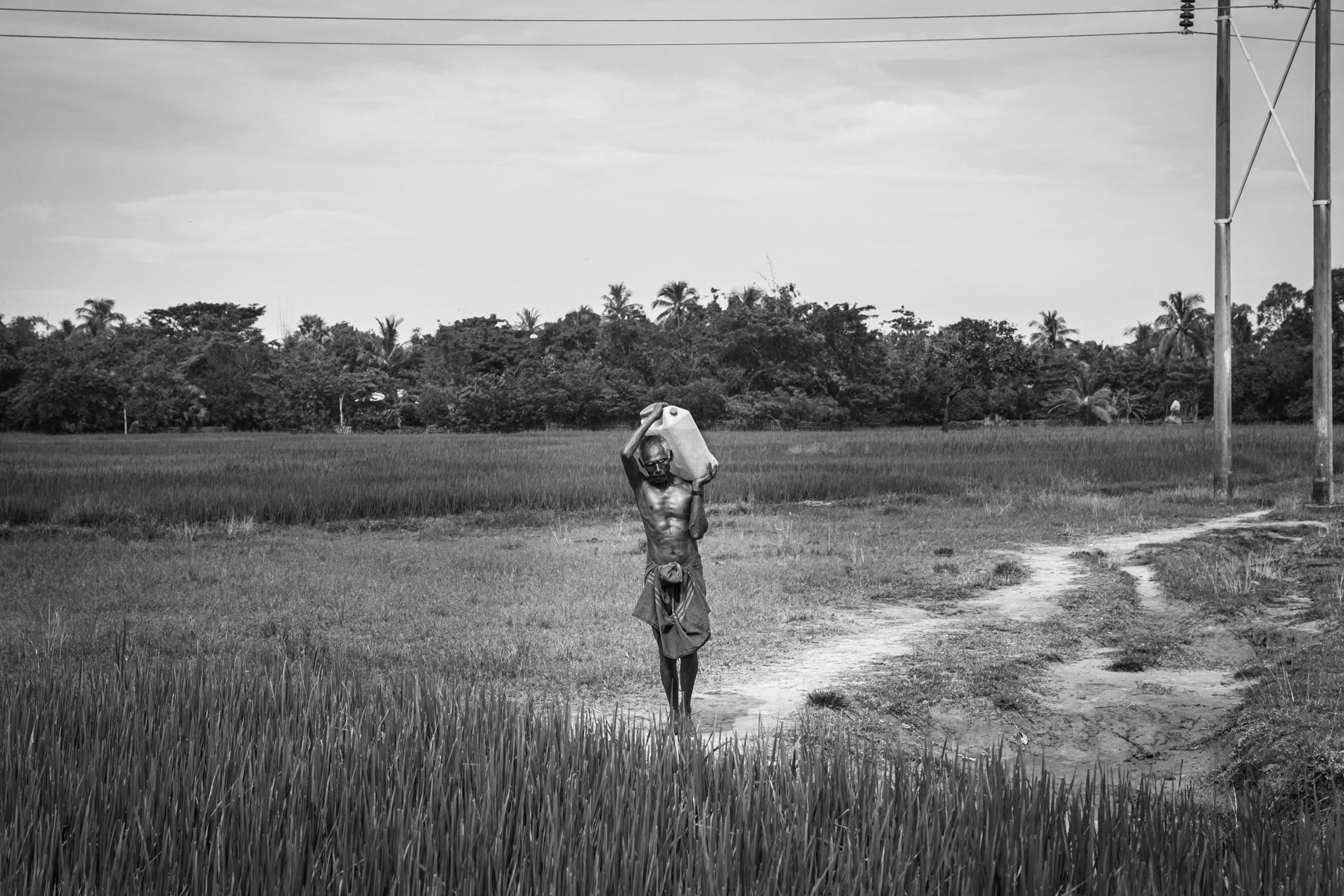A Rohingya man carrying water to his village in Sittwe township. Movements between Rohingya villages and the camps are severely restricted and are completely sealed off from Sittwe town. Rakhine State, Sittwe township, September 2019