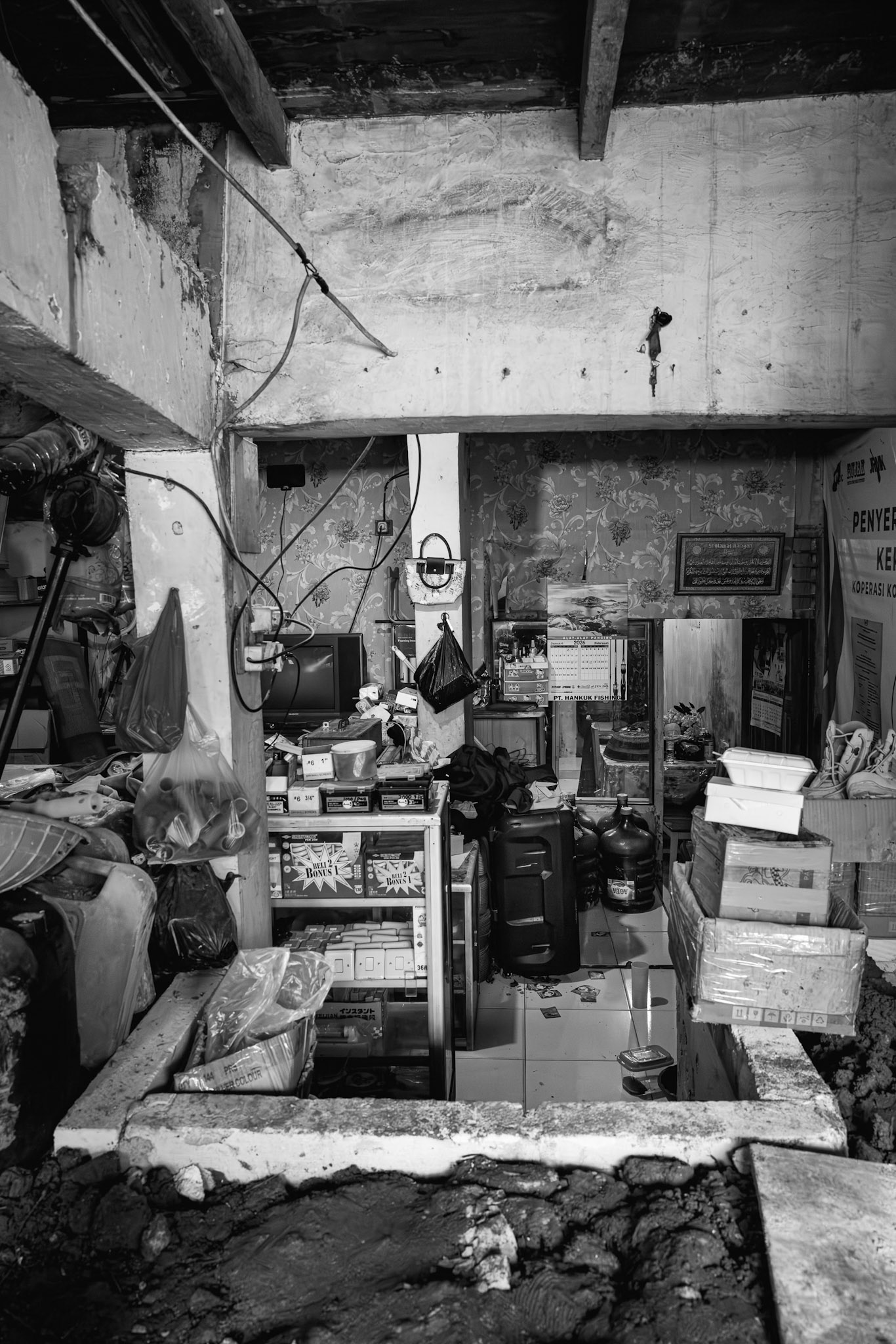 The cramped, dark interior of coastal living where the horizon is blocked by rising ground. Muara Angke, Jakarta, January 2026