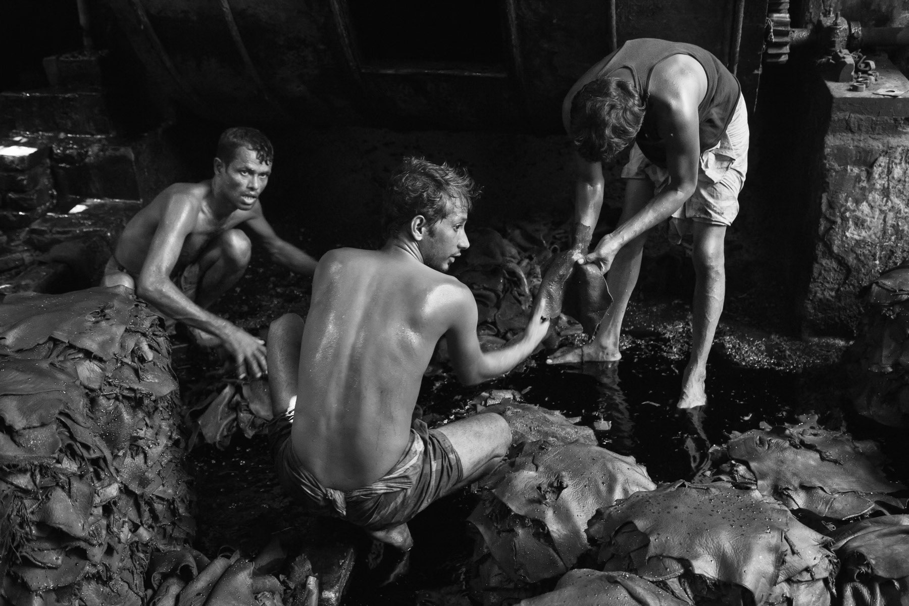 Tannery workers unprotected sorting the skins in a chemical bath, Hazirabagh neighbourhood, Dhaka, Bangladesh, October 2014