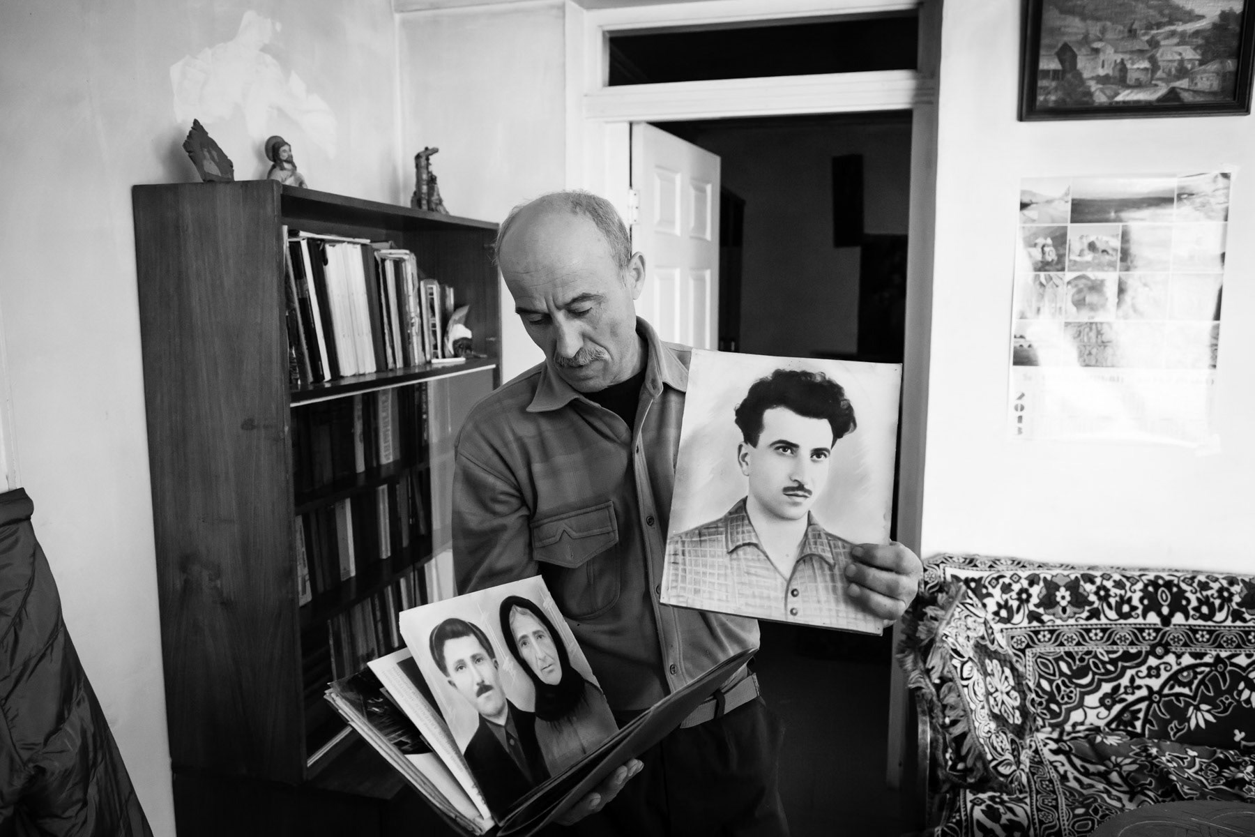 Martin showing family portraits, originally from Verishen in today's Azerbaijan. Refugee in the Karvachar region, Nagorno-Karabakh, February 2014