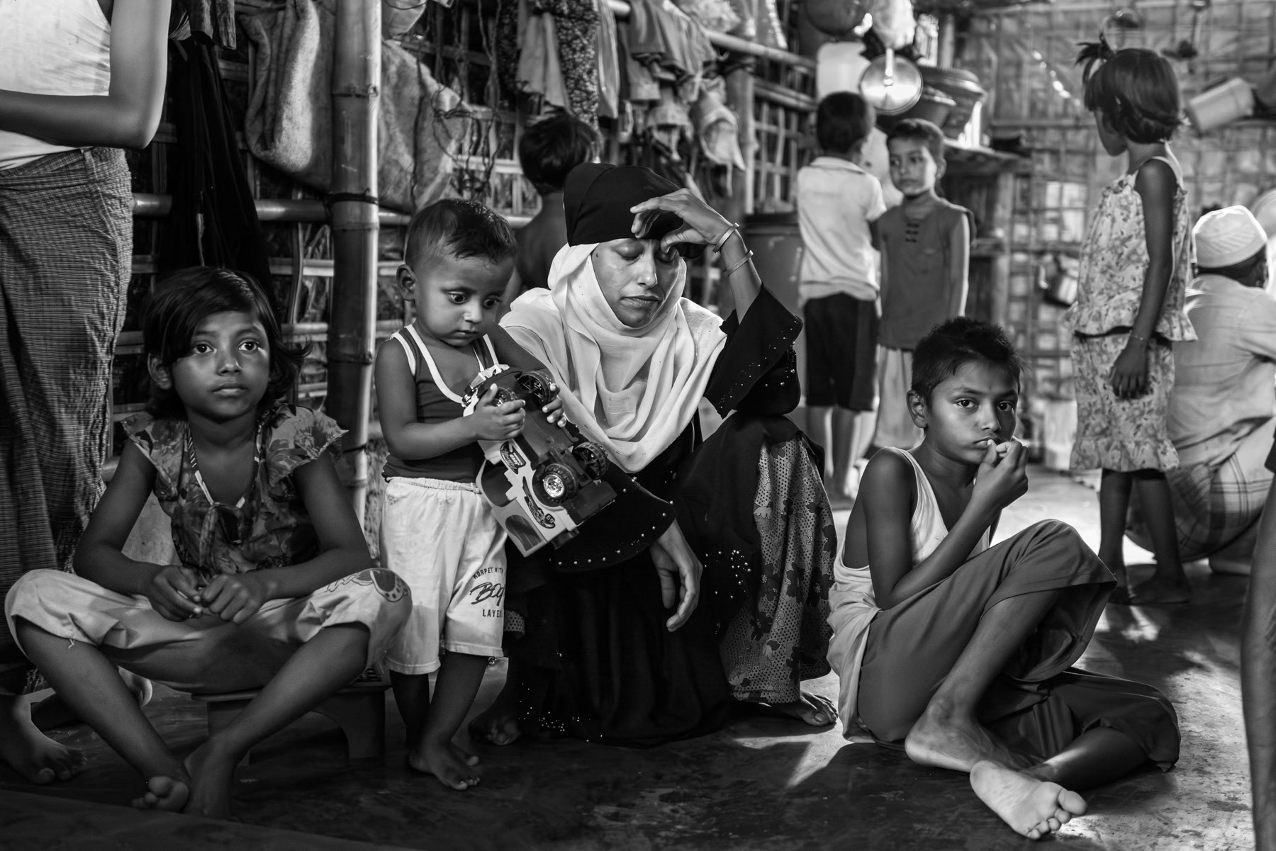 Jana Begum, 30, from Laway Daung in Buthidaung Township, sits with her children inside their shelter in the refugee camp after months of displacement. She fled the village with her family of nine in May 2024, seeking refuge in Ward 5 of Buthidaung. They left the township on 27 January 2025 and reached Bangladesh on 20 February 2025. Kutupalong refugee camp, Ukhiya, Bangladesh, September 2025