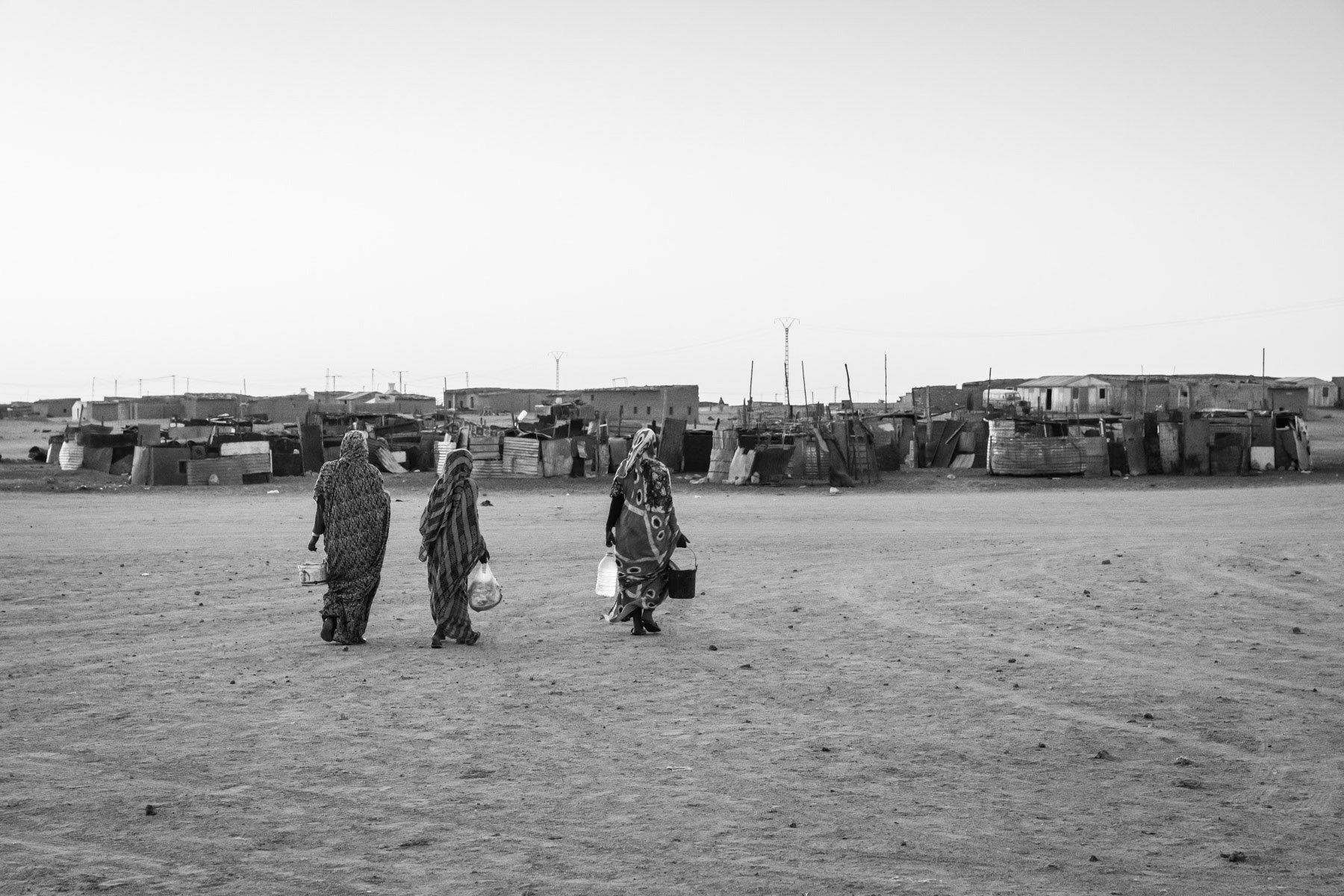 Women carrying water. Smara Saharawi refugee camp and its 30,000 residents. The camp was established more than 40 years ago and only during the past 10-15 years have hard shelters replaced tents. Tindouf, Algeria, December 2019