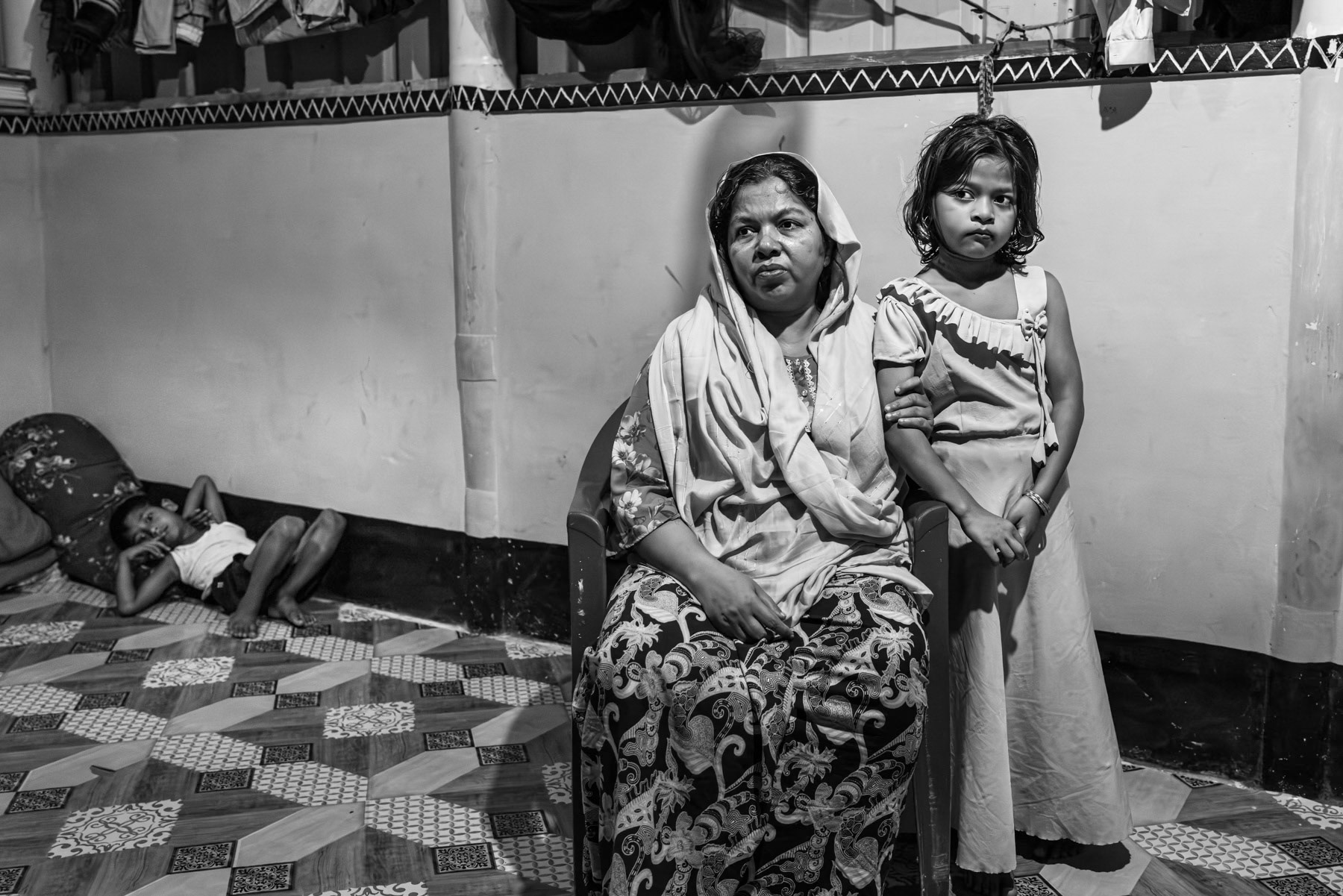 Morija, 40, from Laway Daung in Buthidaung Township, sits with her daughter beside her after fleeing their village following attacks carried out by the Arakan Army in May 2024. She reports that roughly 1,500 people were killed in the area, according to eyewitness accounts. Two to three months before the assault, her husband, Md Noor, 42, a community leader, and her 17-year-old son, Rashed, were arrested by the Arakan Army; she has had no news of them since. Morija escaped to Bangladesh with her four younger children, arriving in December 2024. Kutupalong refugee camp, Ukhiya, Bangladesh, September 2025