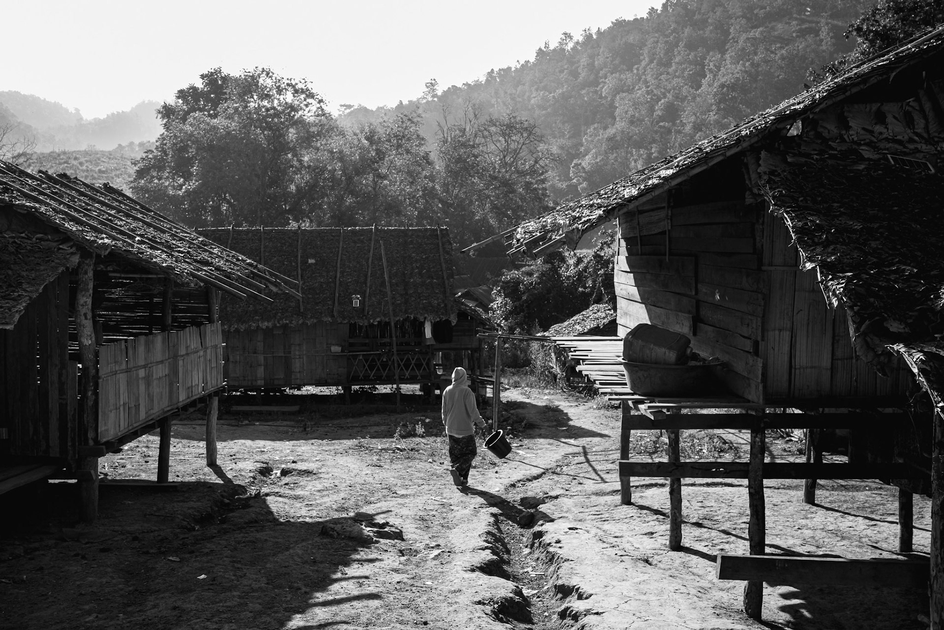 A lone figure walks through the dirt paths of the camp. The infrastructure here is temporary by design, reflecting a population that is caught between the home they lost and a border they cannot fully cross. Kayin State, Myanmar, January 2026