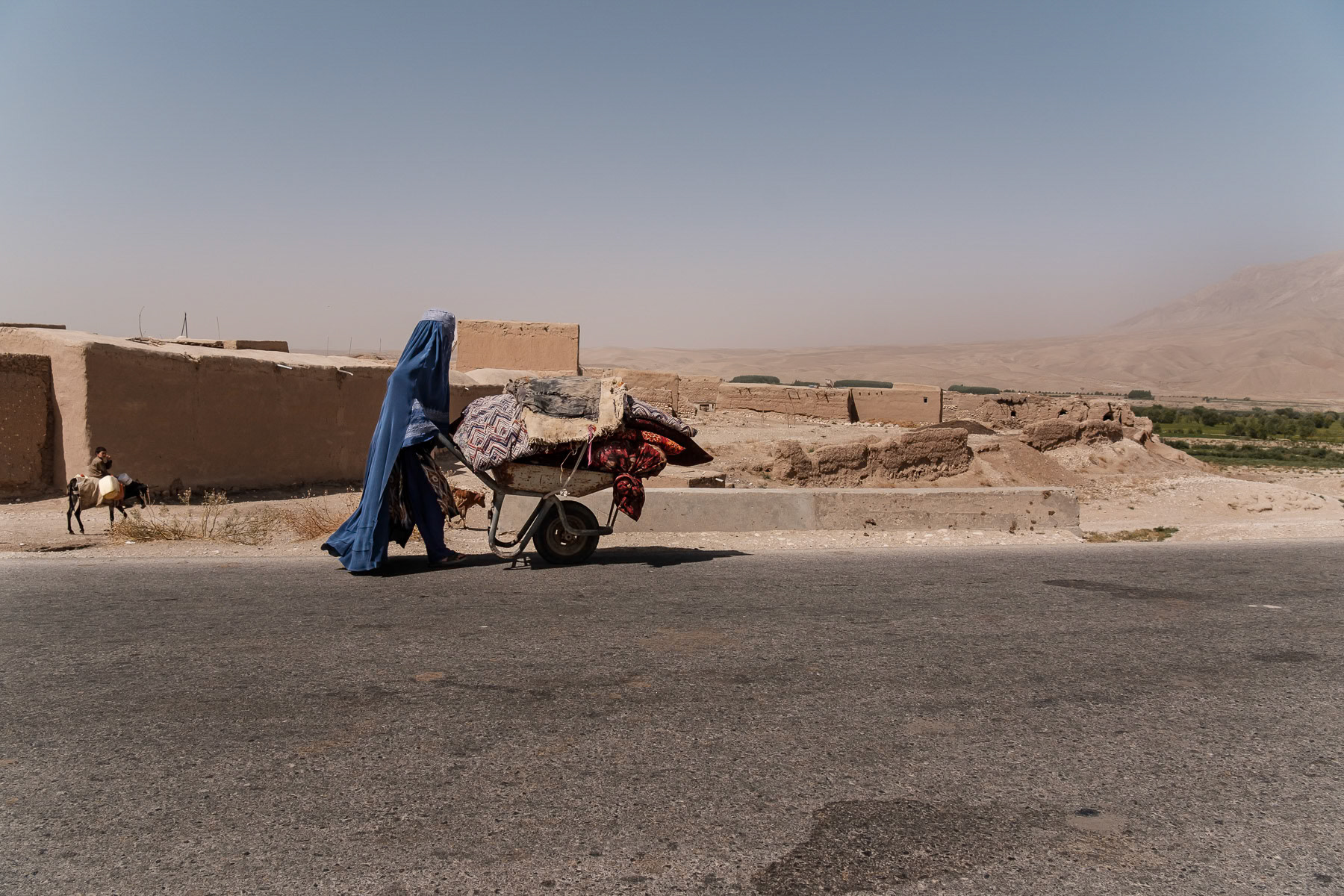 An Afghan woman wearing the 'Chaador' carrying belongings. Since the Taliban take over of the country, endless restrictions have been placed on women, banning them from education, work, cultural activities and basically the streets where they should be accompagnied by a male guardian. Afghanistan under the Taliban has become a 'no woman's land' and a gender apartheid system. Buina Qara, Balkh province, Afghanistan, September 2024