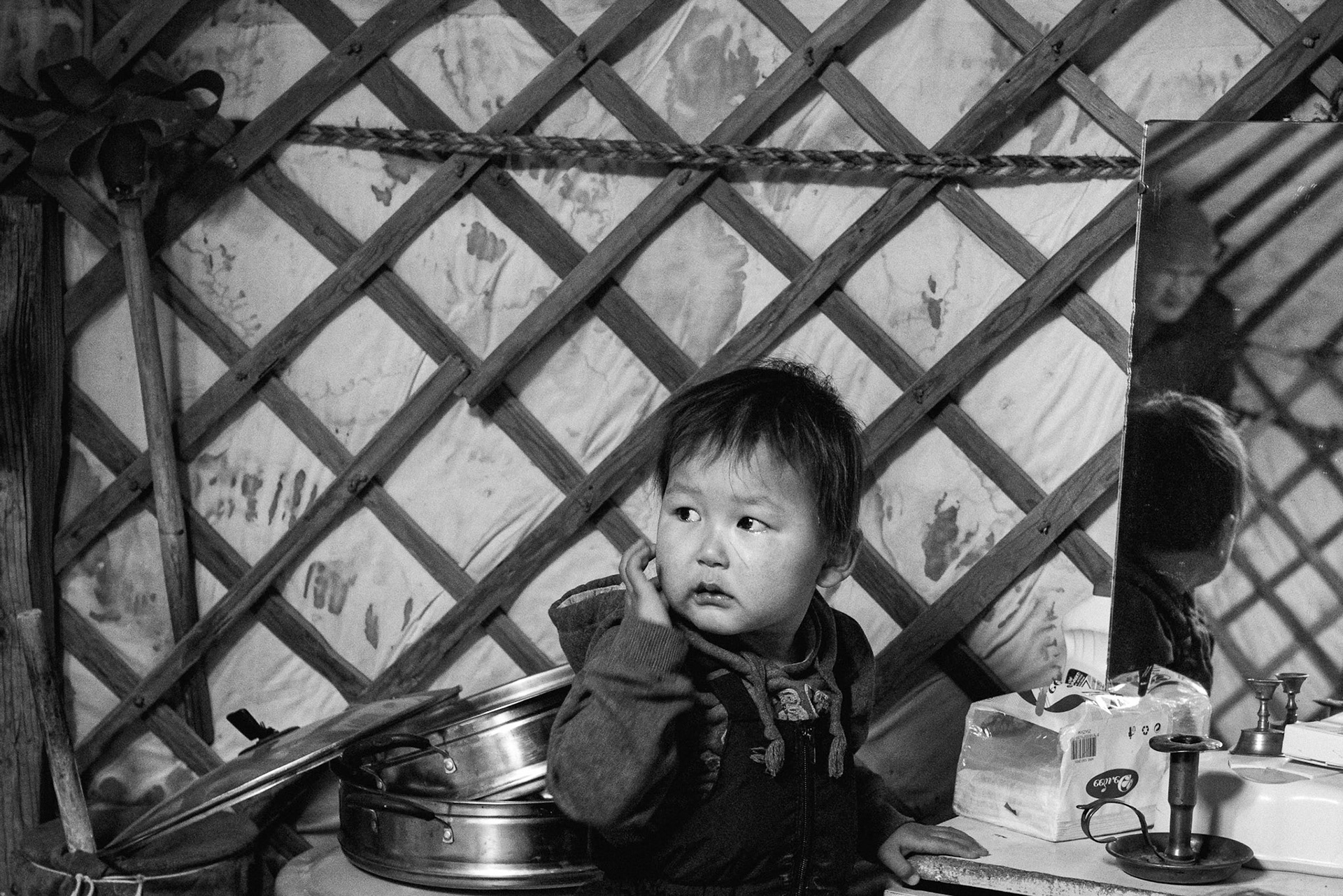 Inside the Ger, the grandfather looks after his grandchildren while their parents work in Ulaanbaatar. Gobi desert, Mongolia, December 2025