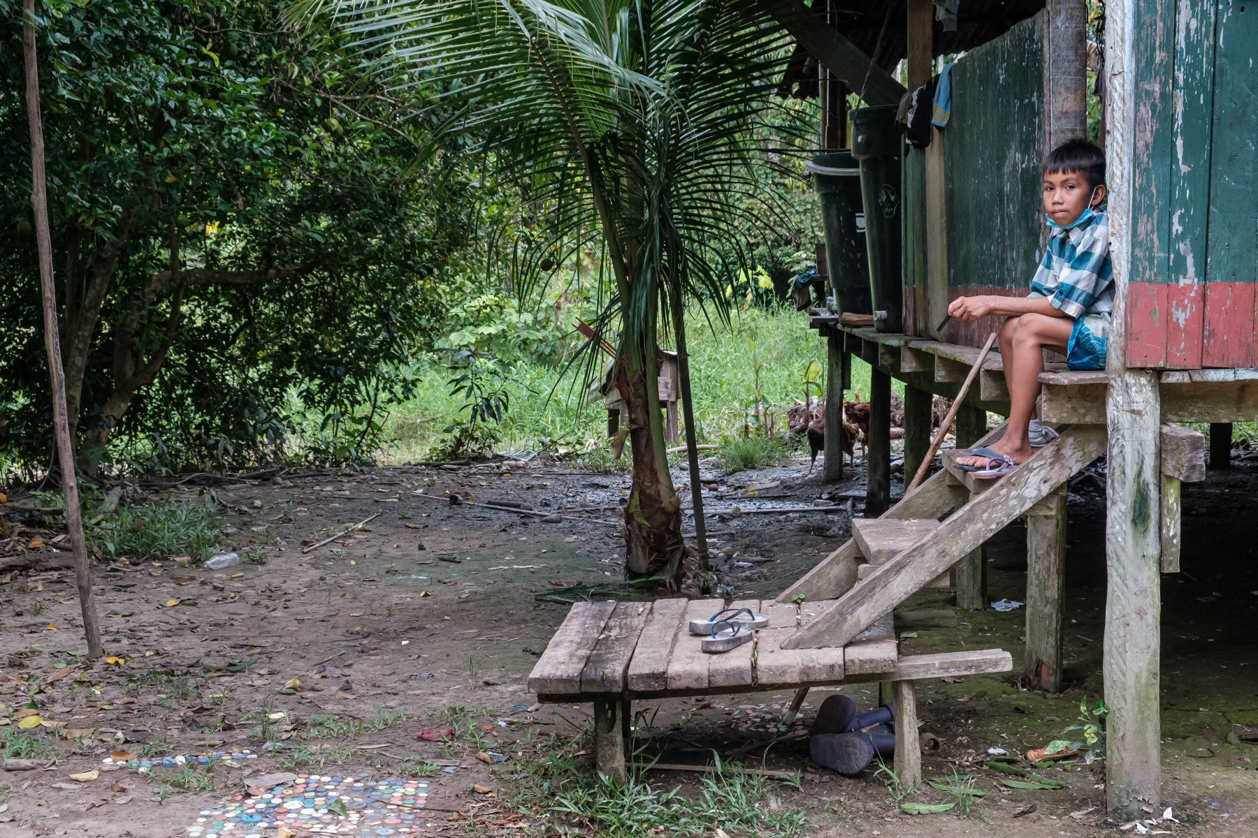 A boy from the Ticuna indigenous community at his typical house on pylons. Indigenous community of San Antonio de Cacao, Peru, April 2022