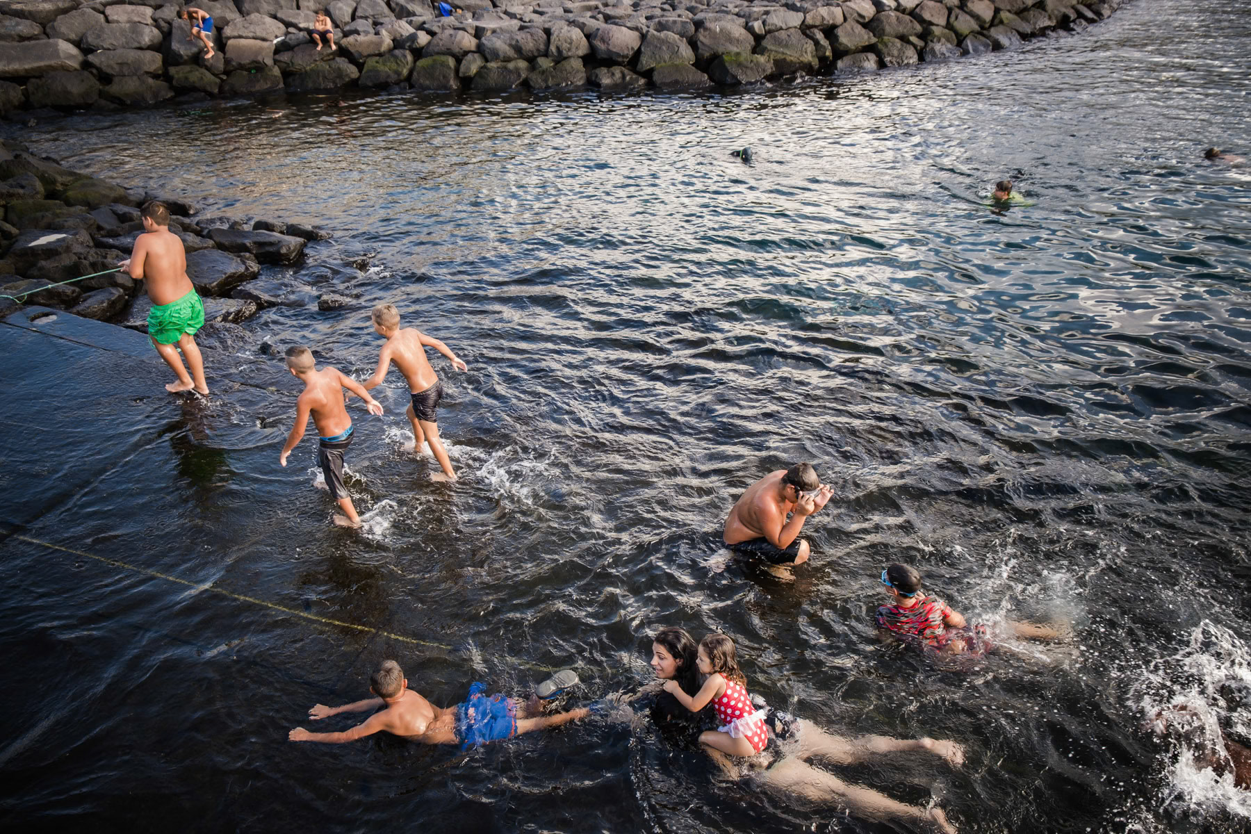 Kids playing and swimming in the port. Rabo de Peixe, Azores, September 2018