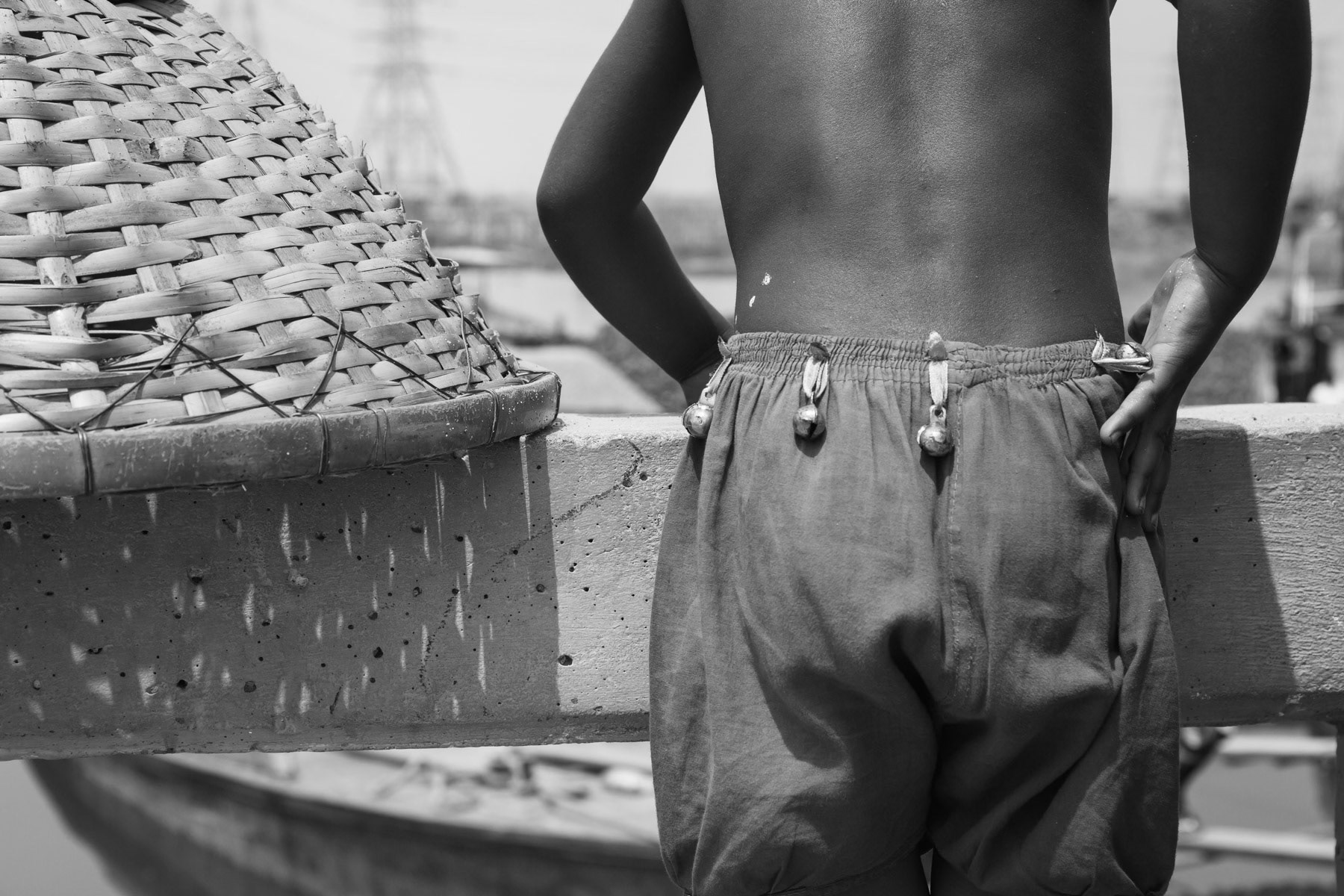 Child with location bells overlooking boats being unloaded, Gabtoli terminal, Bangladesh, May 2015
