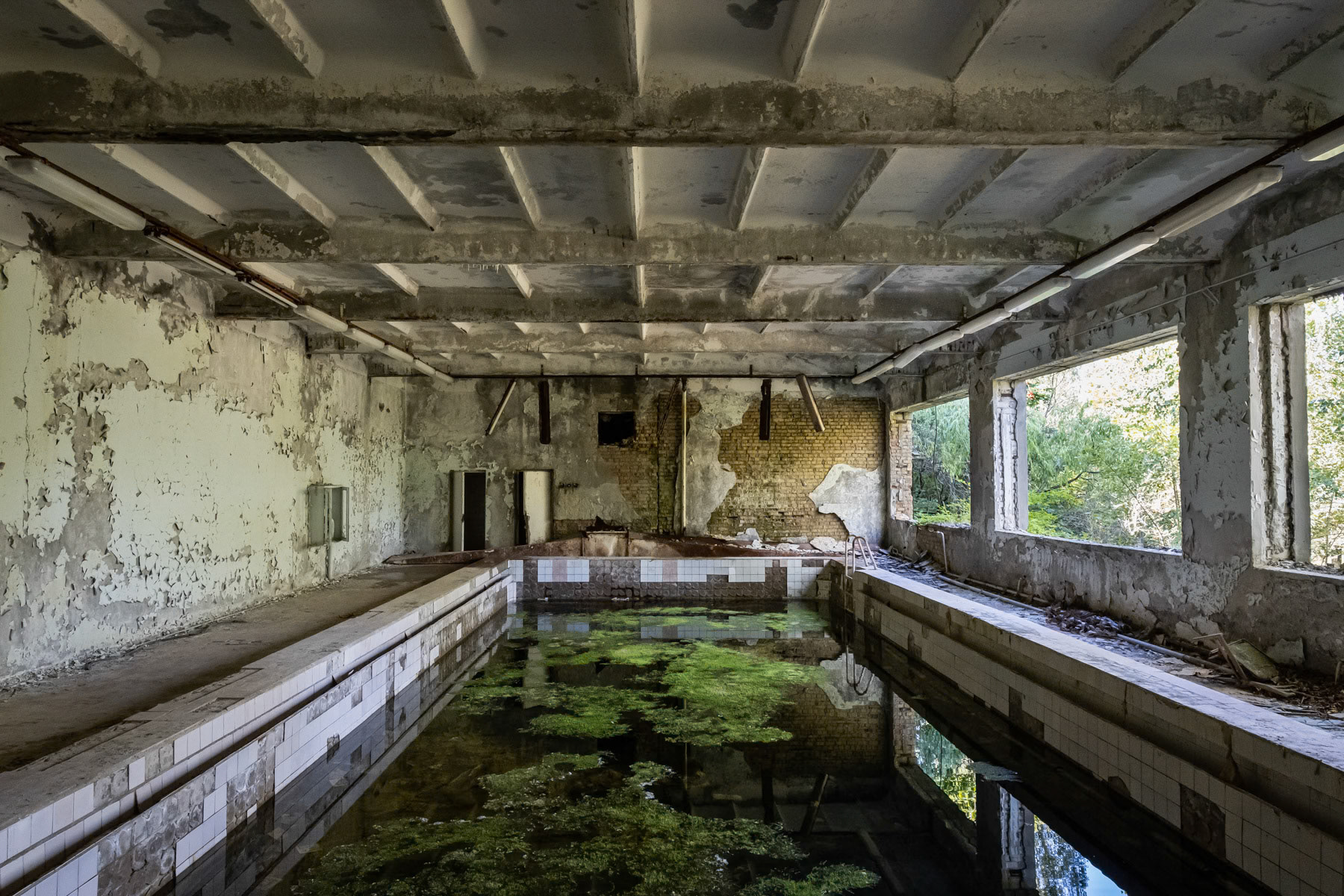 Swimming pool at a school in Pripyat town. The town was developed alongside the nuclear power plant to house staff and their families. Before the disaster it consisted of 5 districts, each of them with well-developed infrastructure. There were 5 schools, 14 kindergartens, a cinema, swimming pools, theatre, shopping centres and residential buildings for 30,000 people with extensions planned of at least one more district near the port area. The complete population of Pipyat was evacuated 36 hours after the disaster to never return again. Pripyat is now an overgrown ghost town where time stood still on 27 April 1986. Pripyat, Chernobyl NPP, Ukraine, June 2021