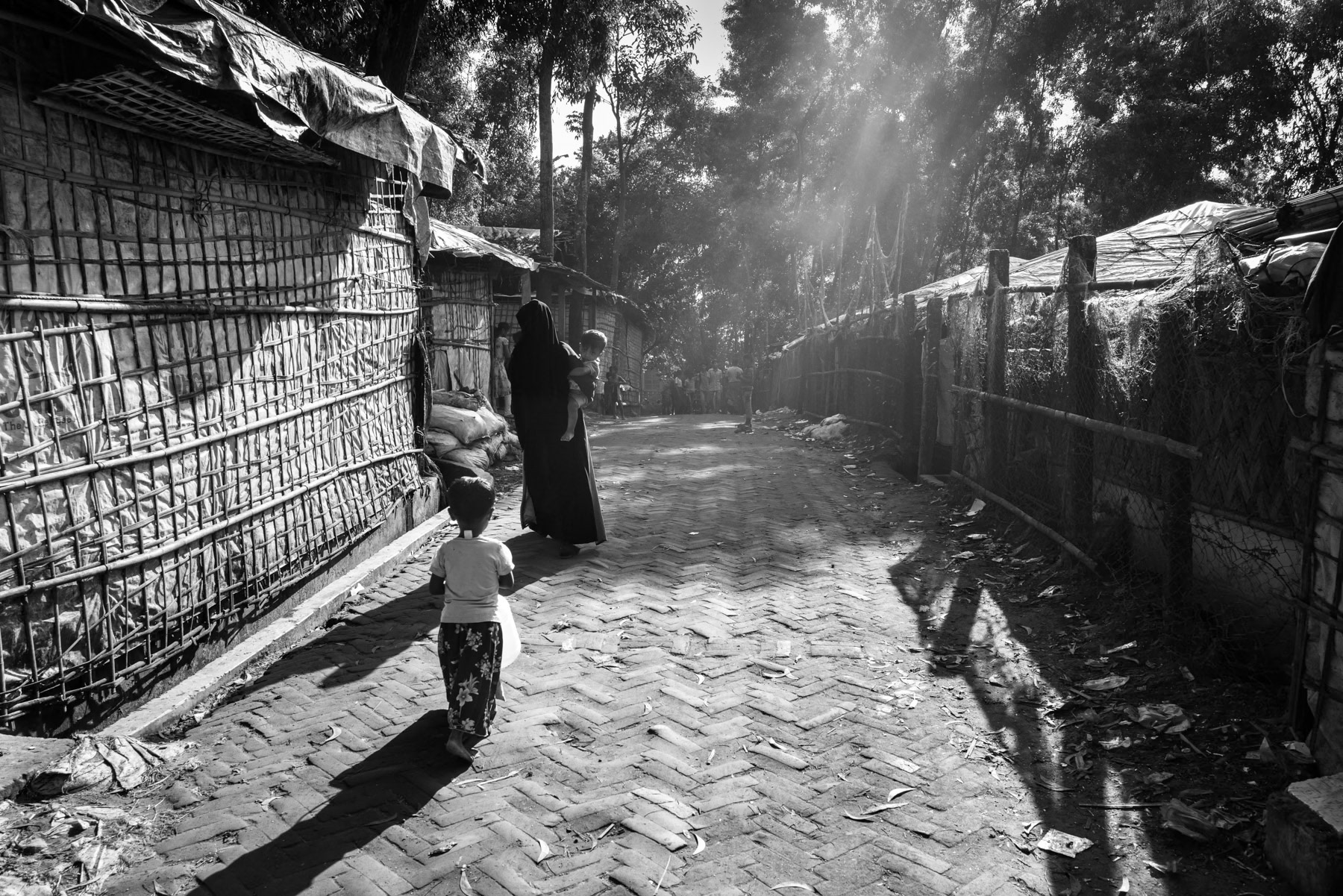 Early morning light illuminates a paved market alley in the camp, quiet and empty before the day begins. Kutupalong refugee camp, Ukhiya, Bangladesh, September 2025